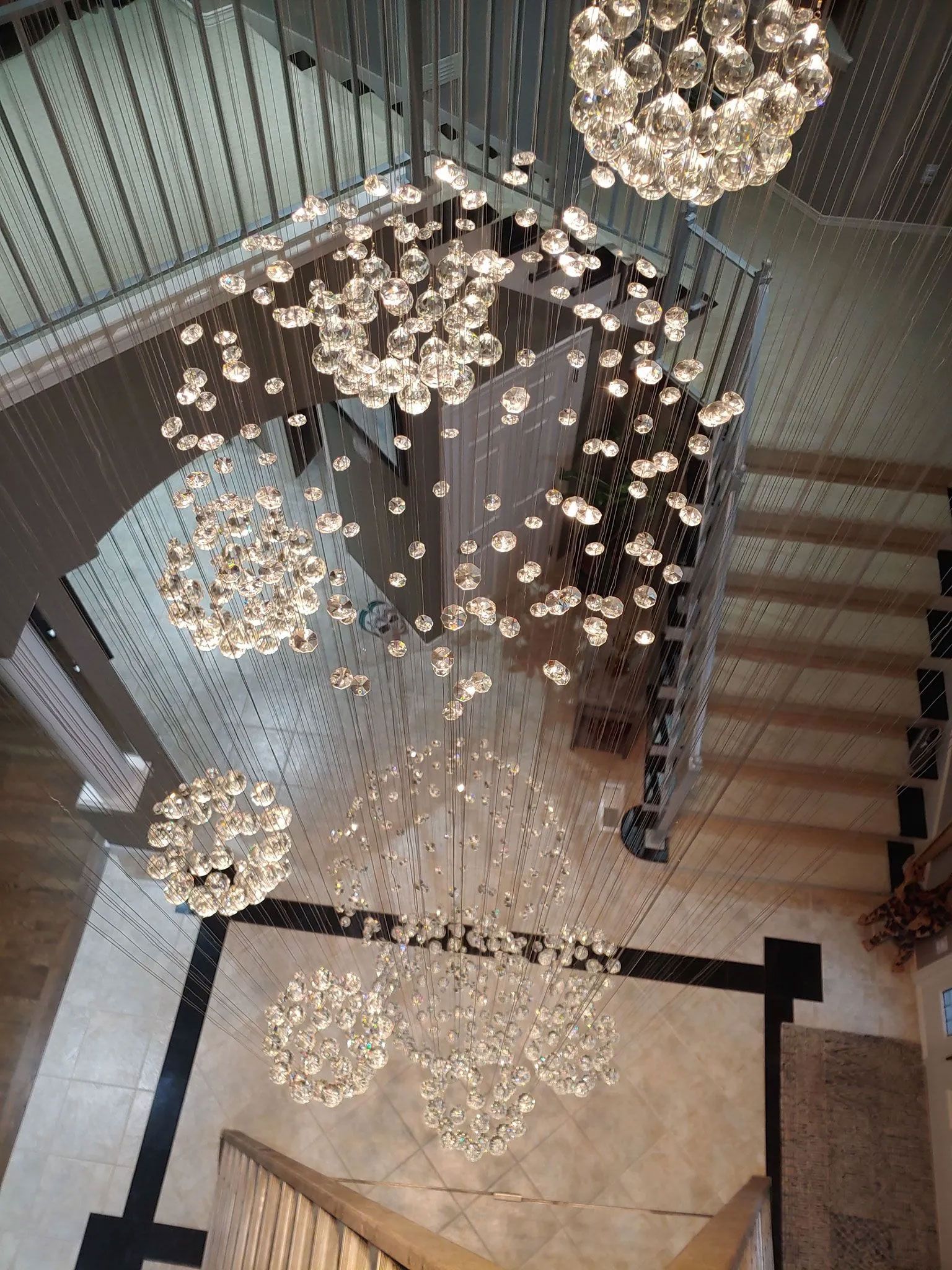 Elegant chandelier over a staircase, composed of many crystal spheres, from a high angle view.