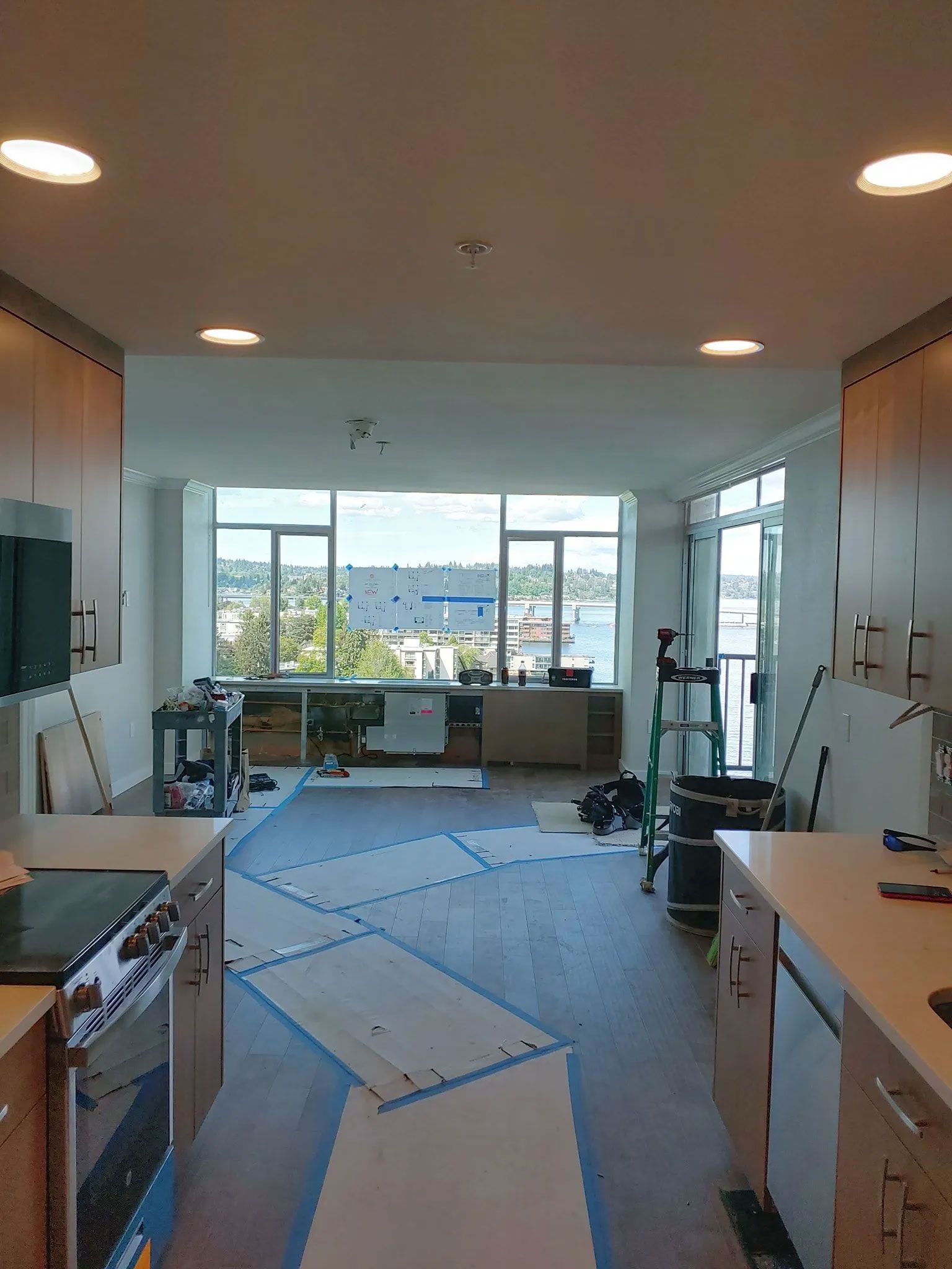 Kitchen with island counters, appliances, and window overlooking a body of water. Construction materials are on the floor.