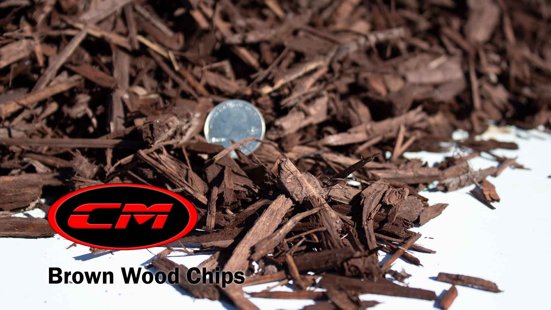 Brown wood chips with a quarter for scale; CM logo.