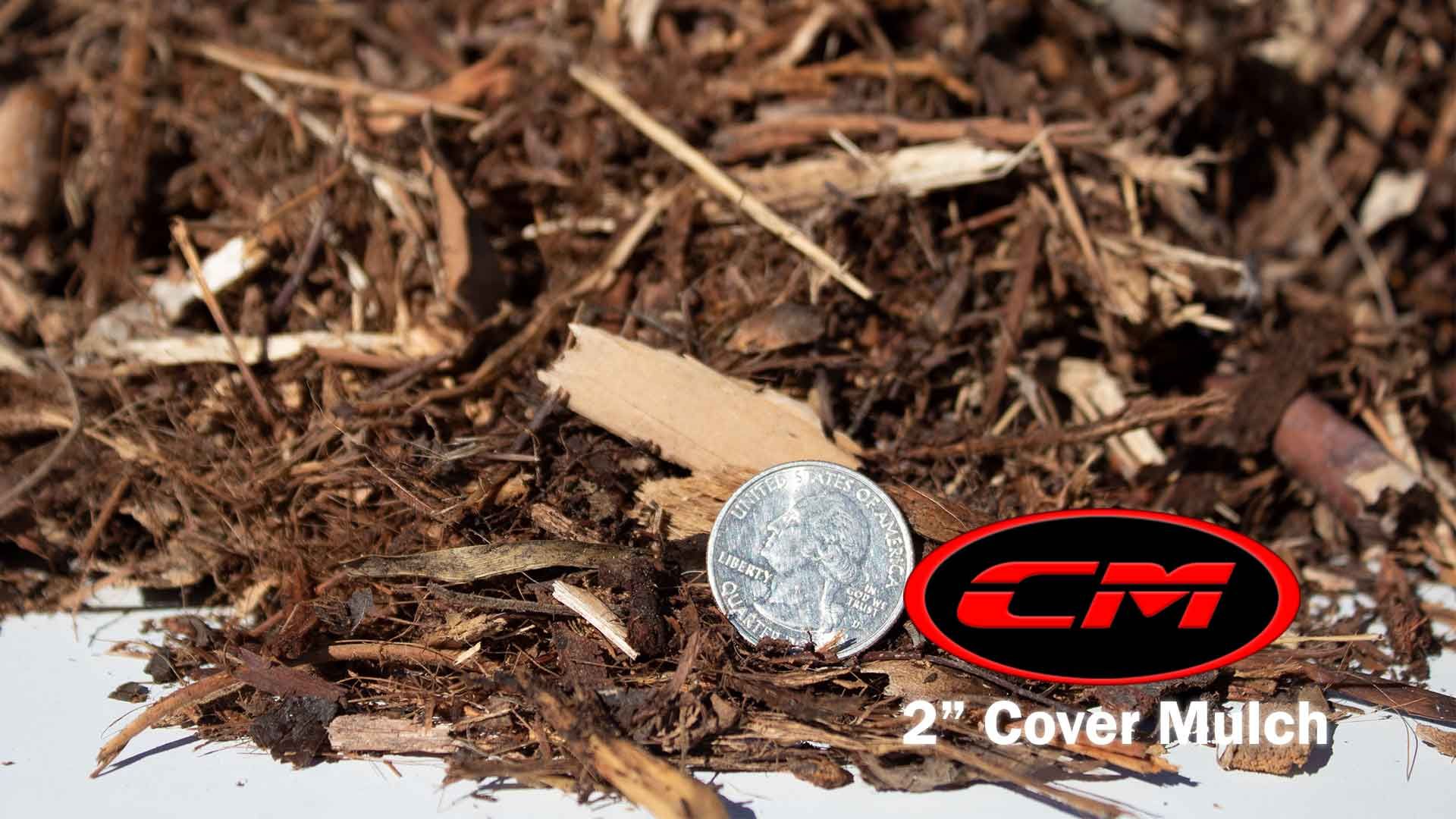 Close-up of brown mulch with a quarter coin for size comparison; CM logo.