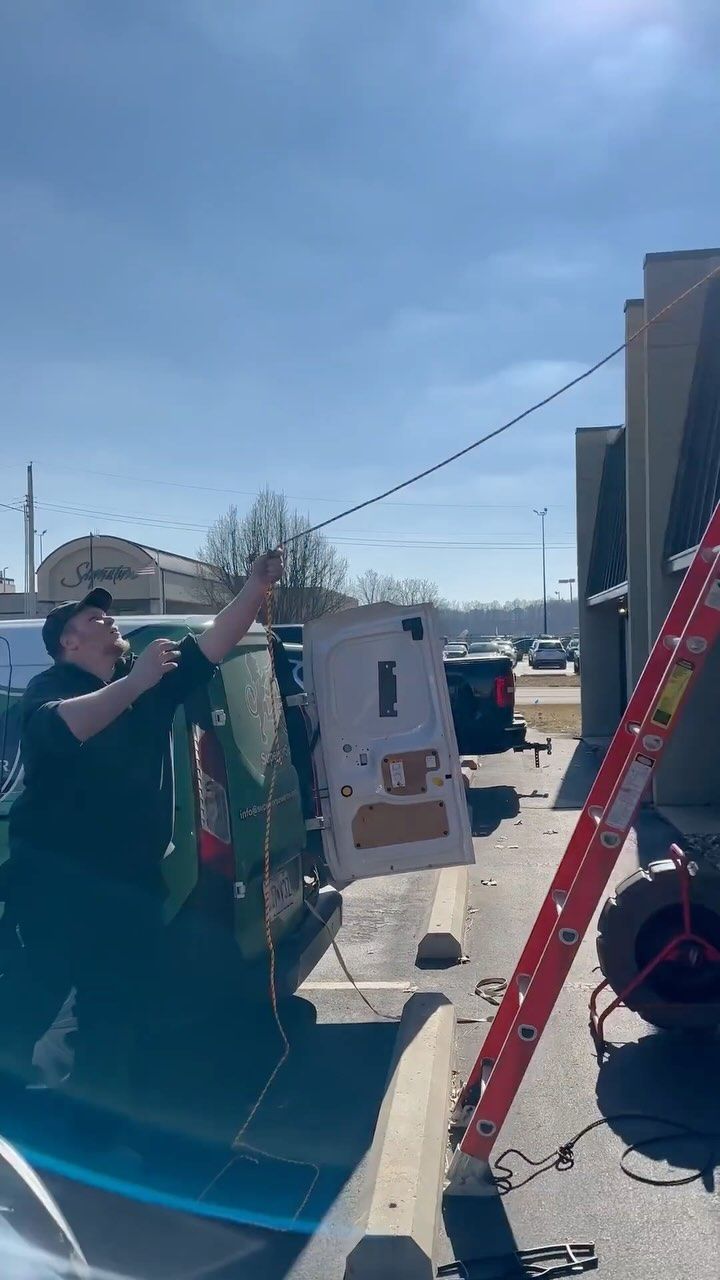 A man is holding a piece of paper in a parking lot next to a ladder.