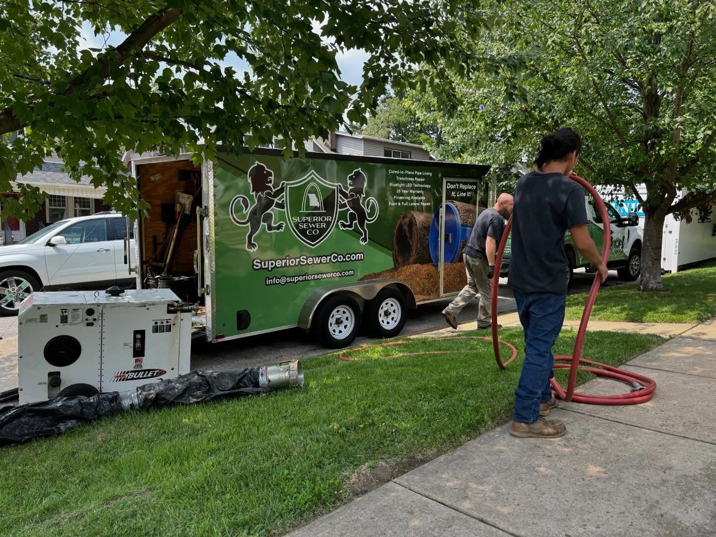 A man is holding a hose in front of a green truck.