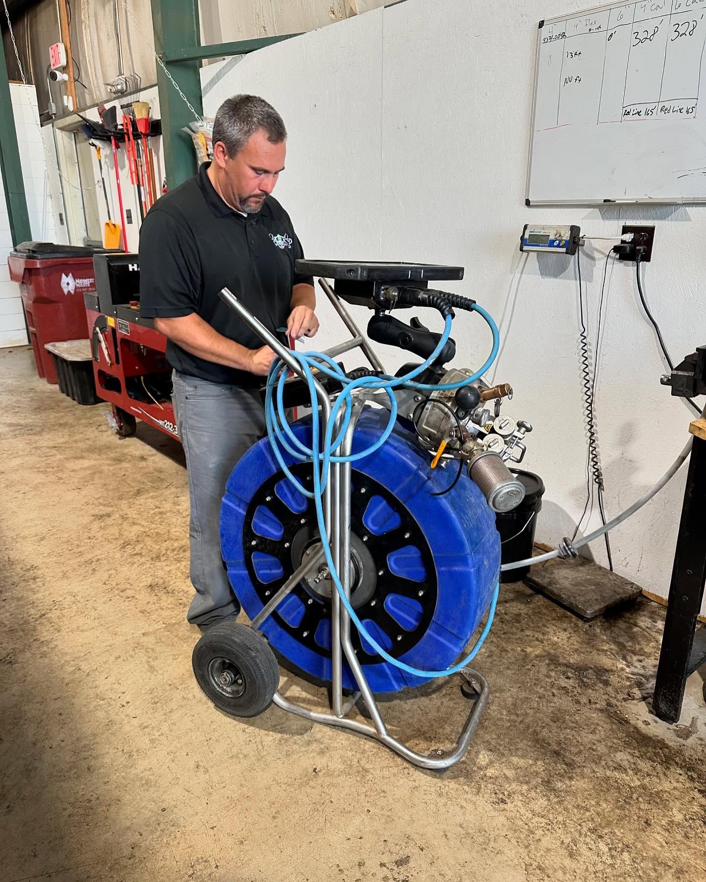 A man is standing next to a large blue hose on a cart.