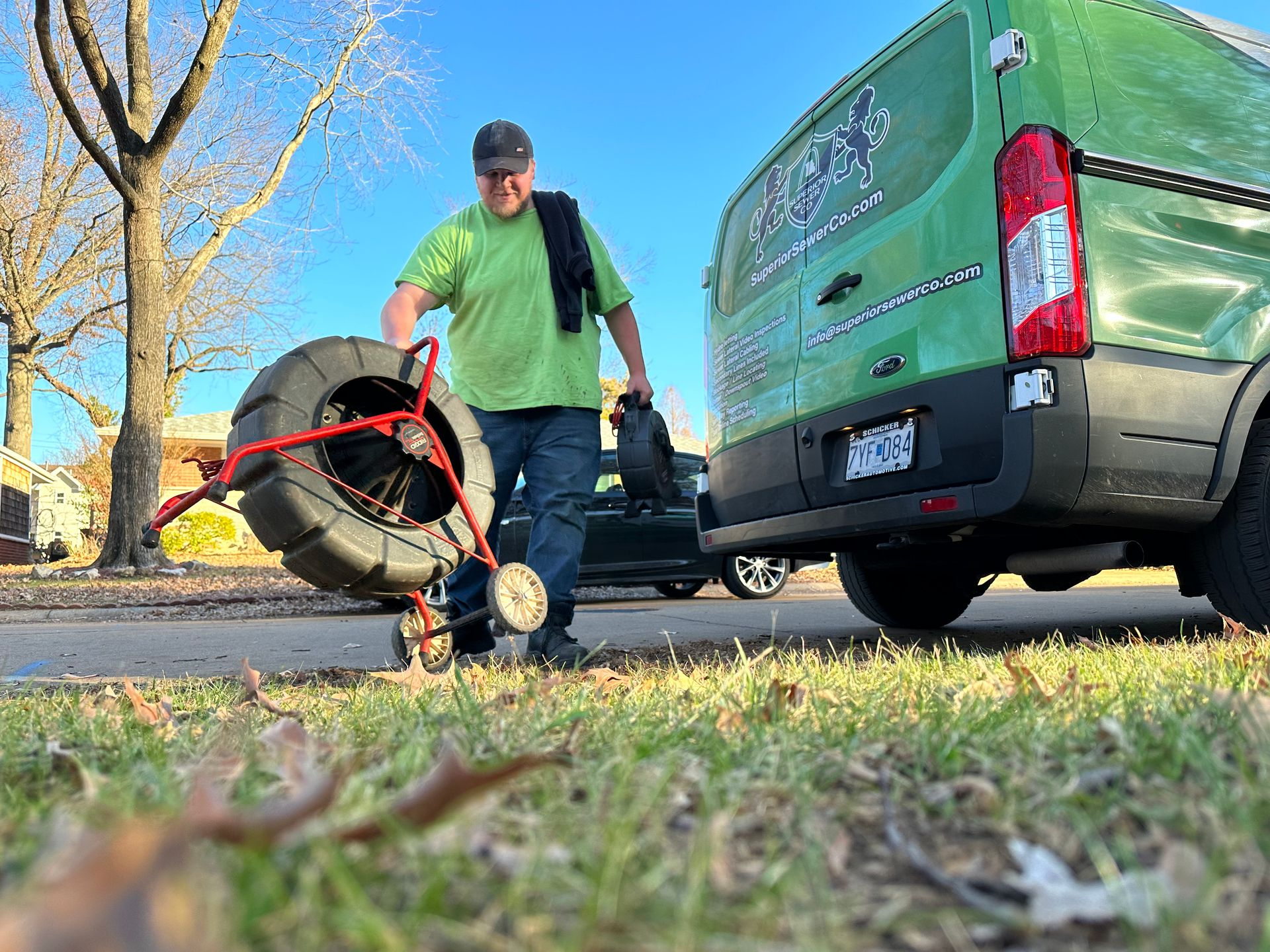 A man is standing next to a green van holding a large tire.