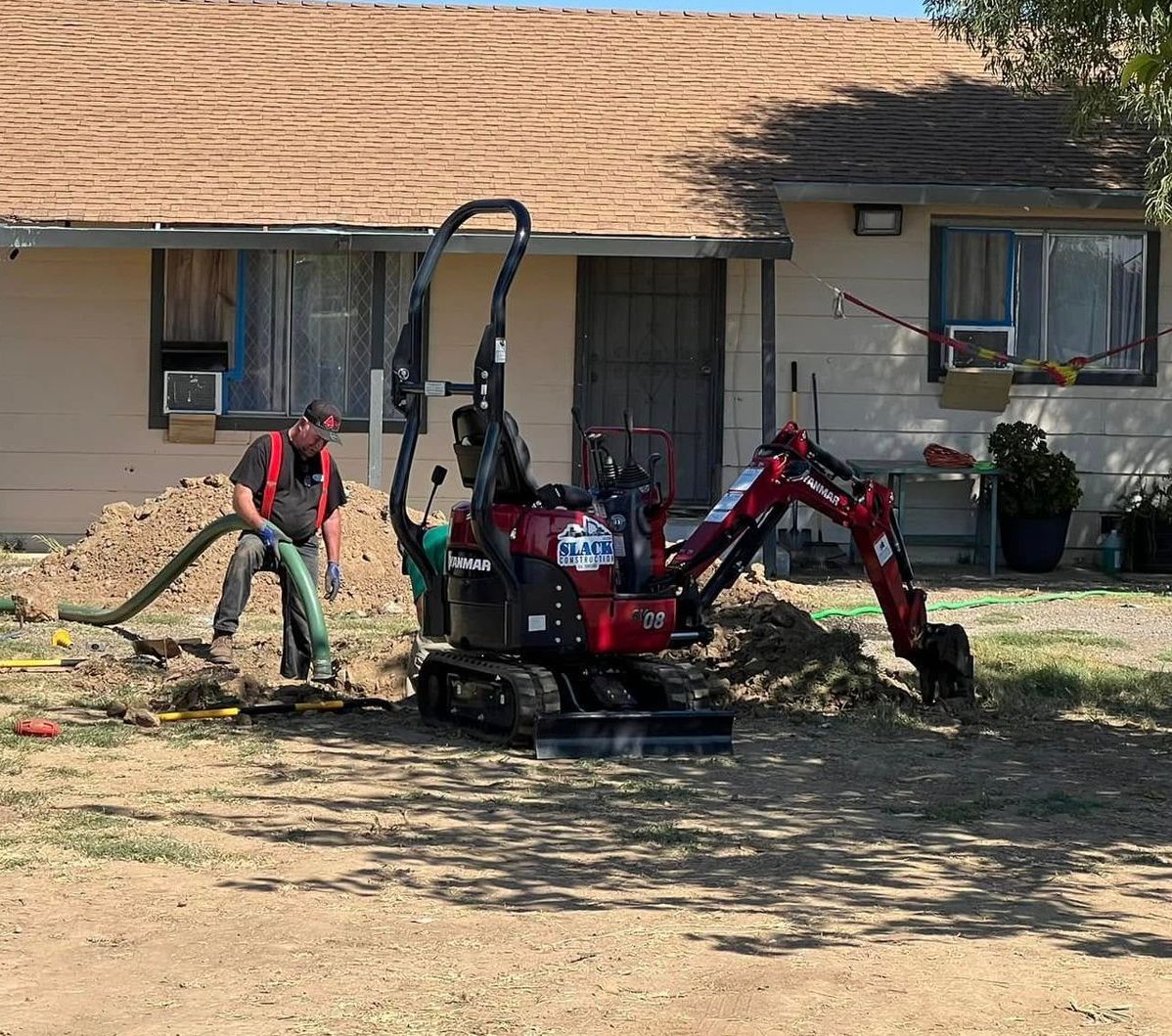A small red excavator is parked in front of a house.