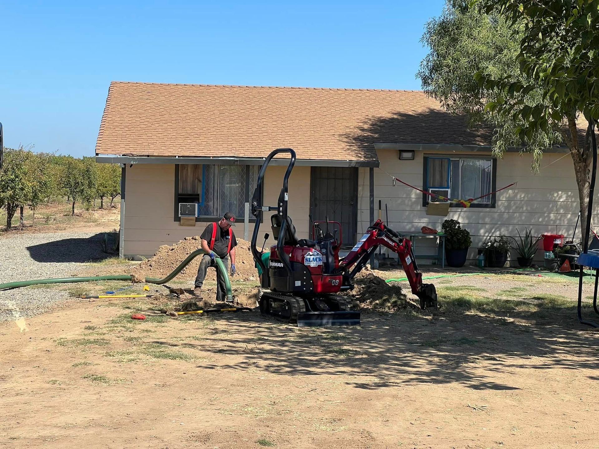A small red excavator is parked in front of a house.