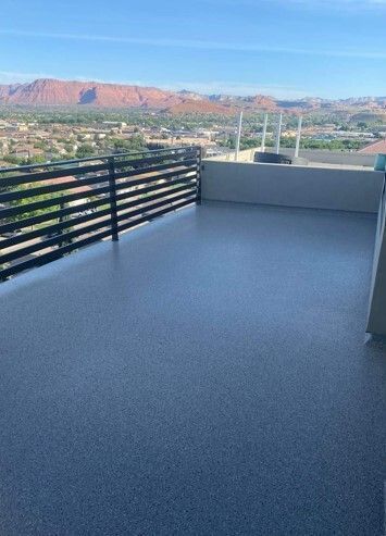 Rooftop deck with dark gray surface, black railing, and distant red rock mountains.