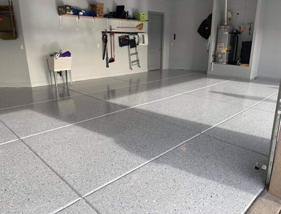 Polished garage floor with gray flecks, divided by lines. Sunlight streams across the floor.
