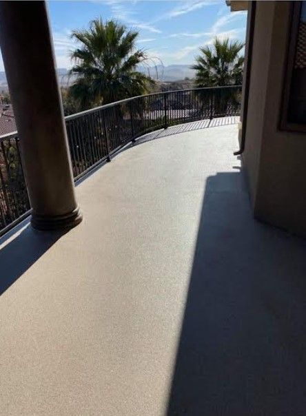 Curved beige deck with black railing and palm trees, sunny daytime.