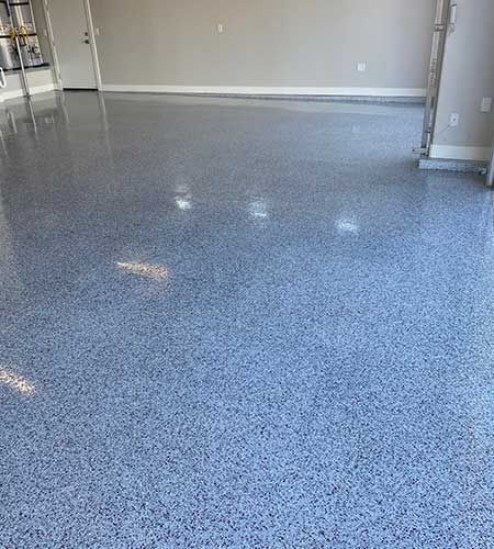 Epoxy-coated garage floor with blue and gray chips, reflecting light.