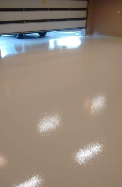 Light beige, glossy, concrete floor; a partially open, white garage door is in the background.