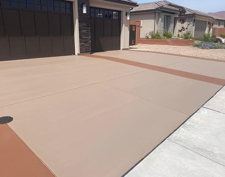 Tan concrete driveway with a brown border leading to a garage.