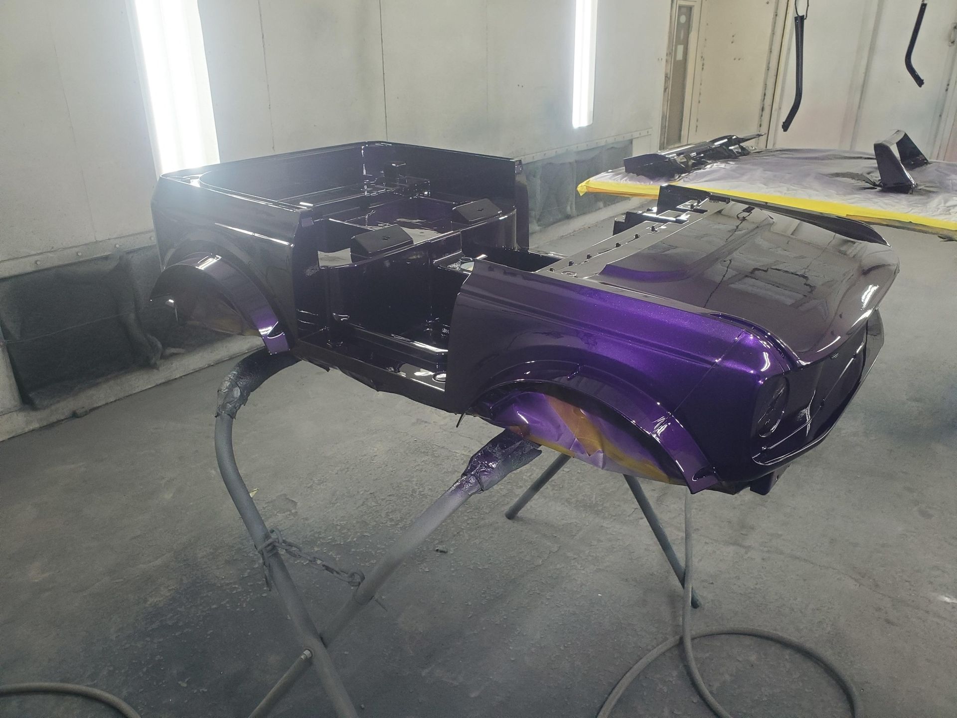 Purple vehicle body being painted in a spray booth.