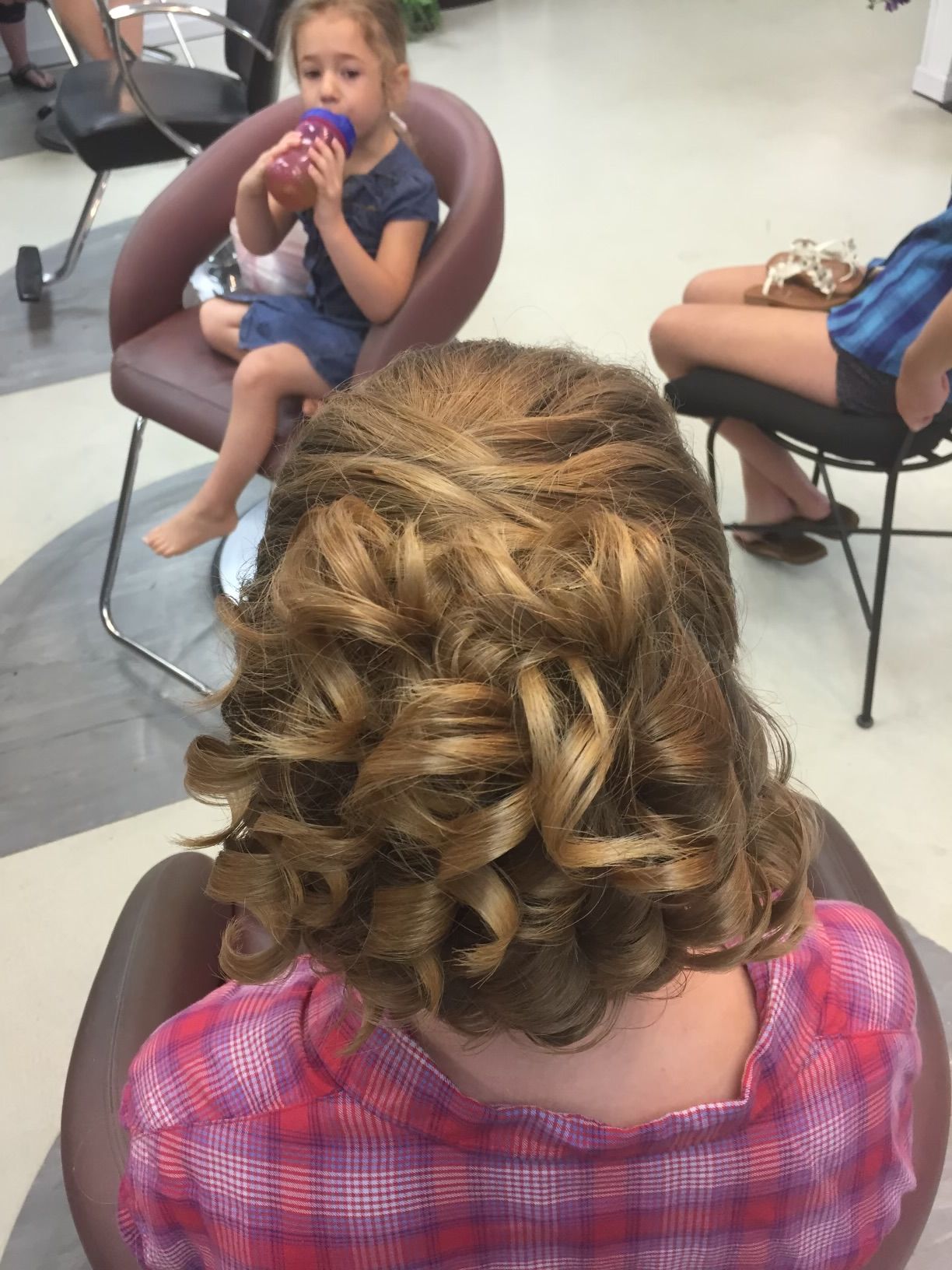 A woman is sitting in a chair with her hair in a bun.