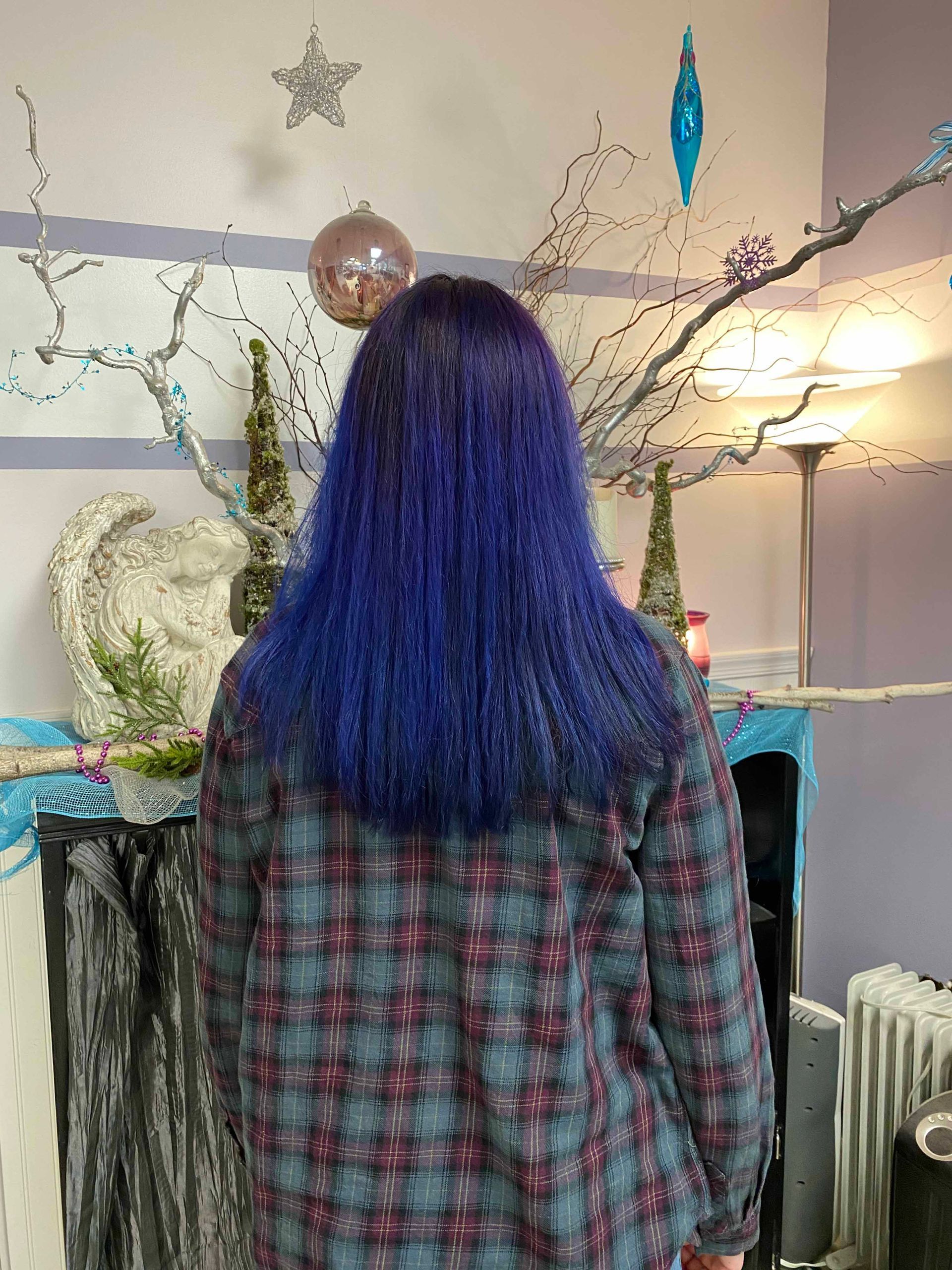 A woman with blue hair is standing in a living room.
