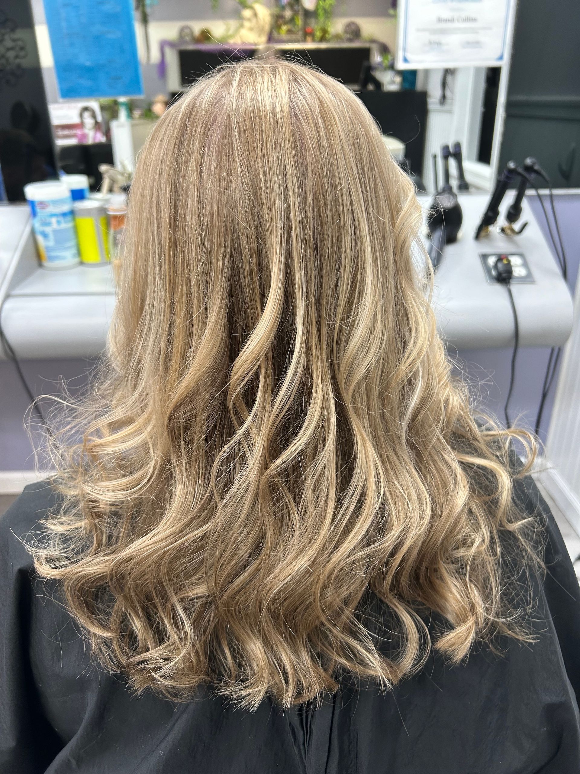 A woman with blonde hair is sitting in a chair in a salon.