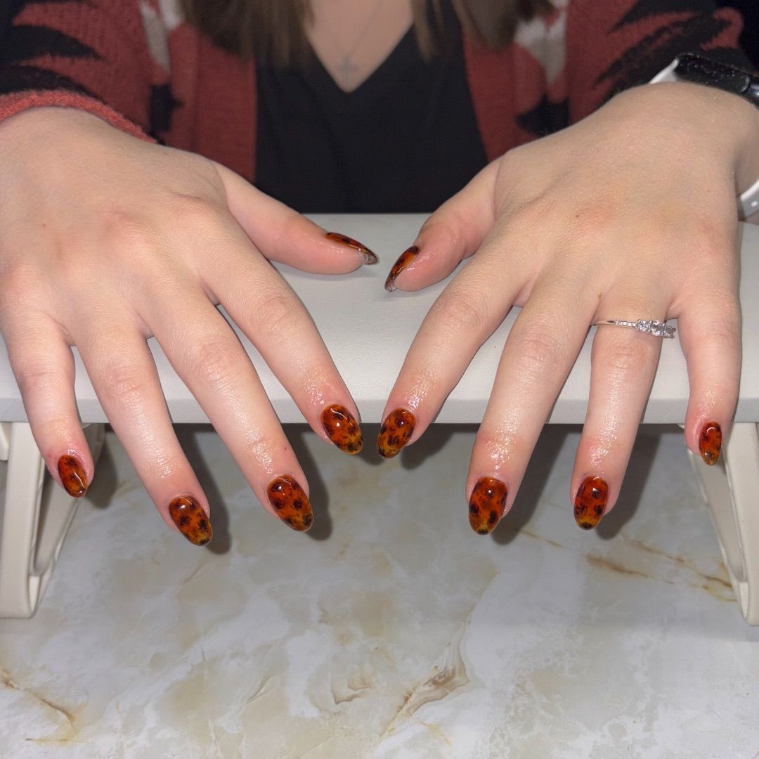 A woman's hands with a tortoise manicure design.