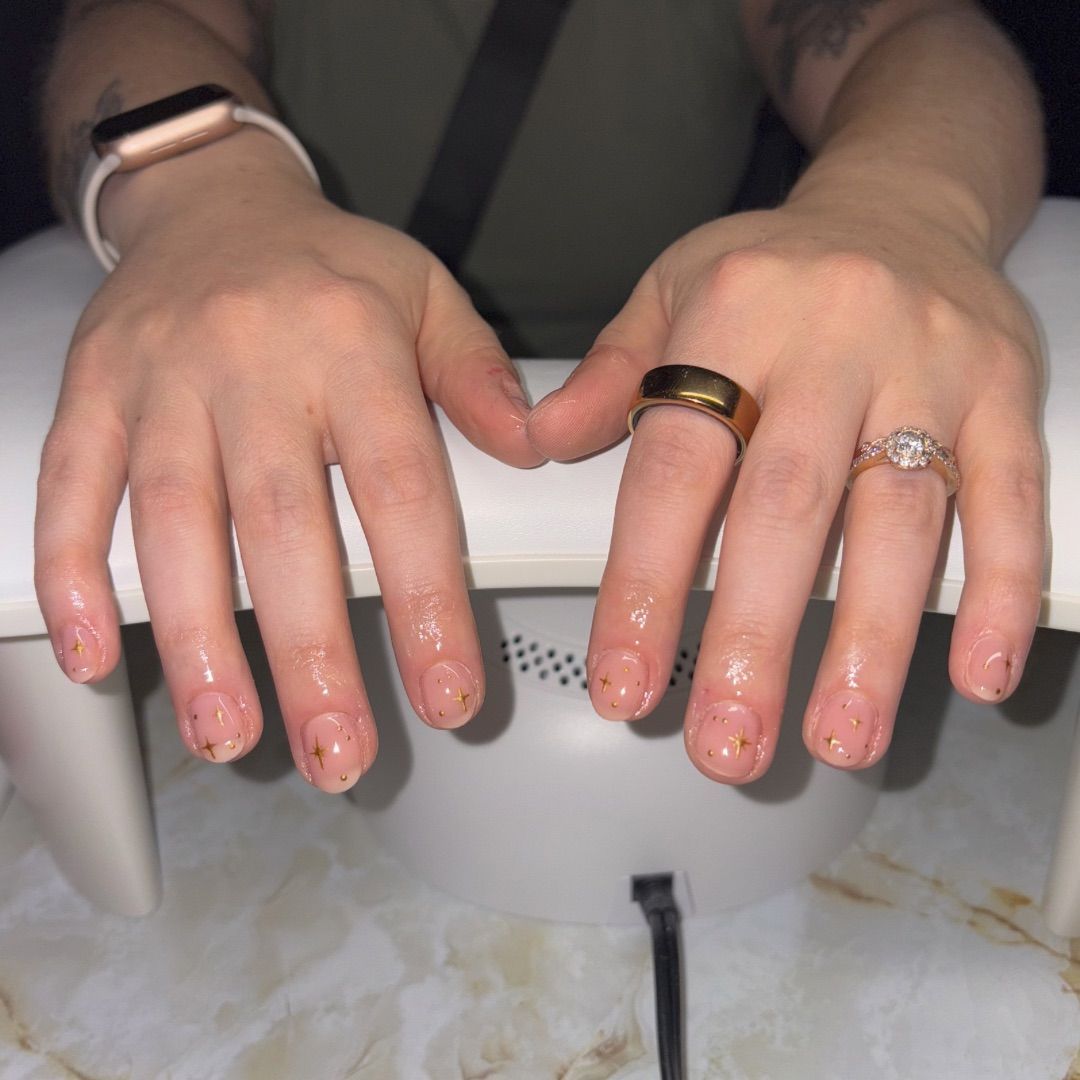 A woman's hands with gold stars manicure design.