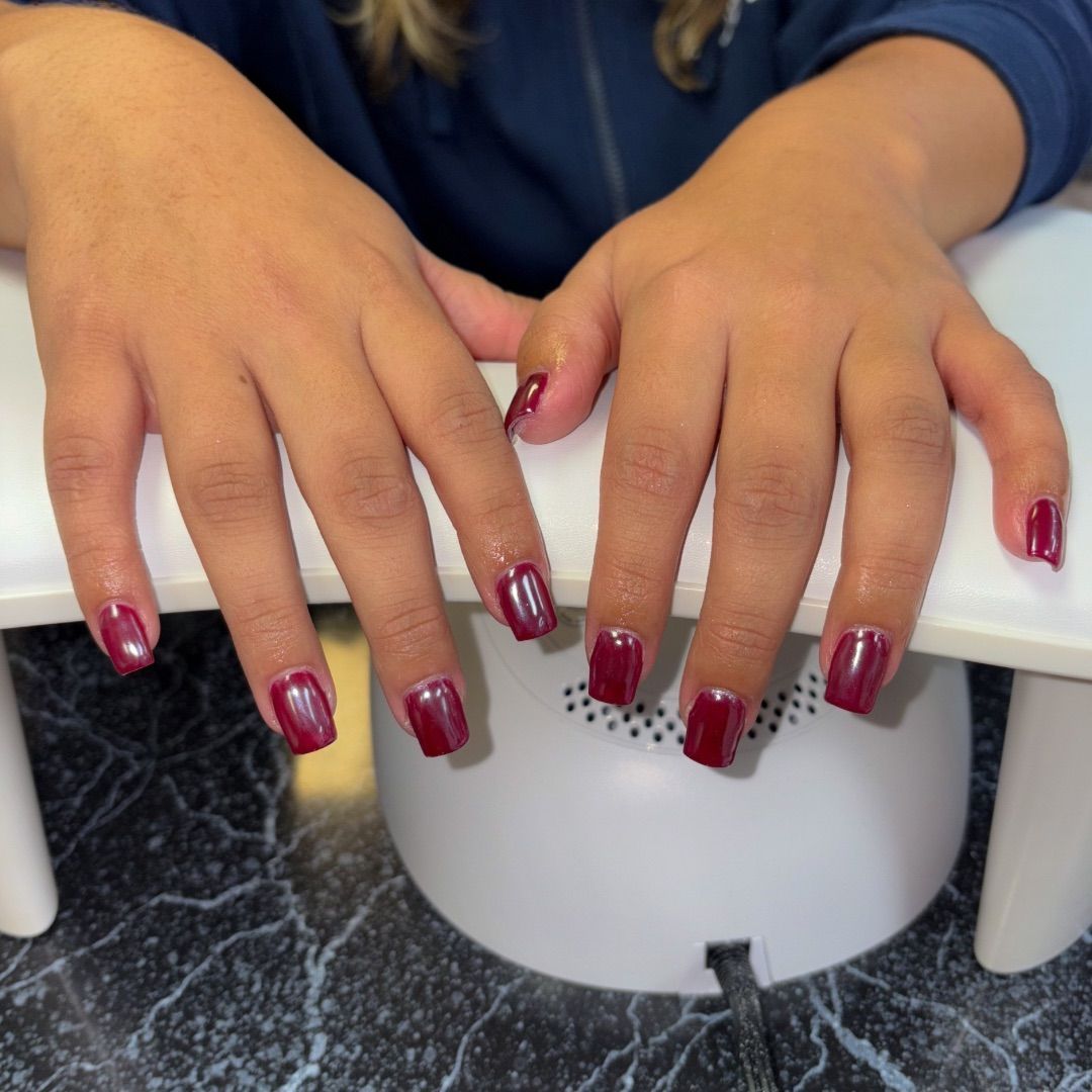 A woman's hands with a red chrome manicure design.
