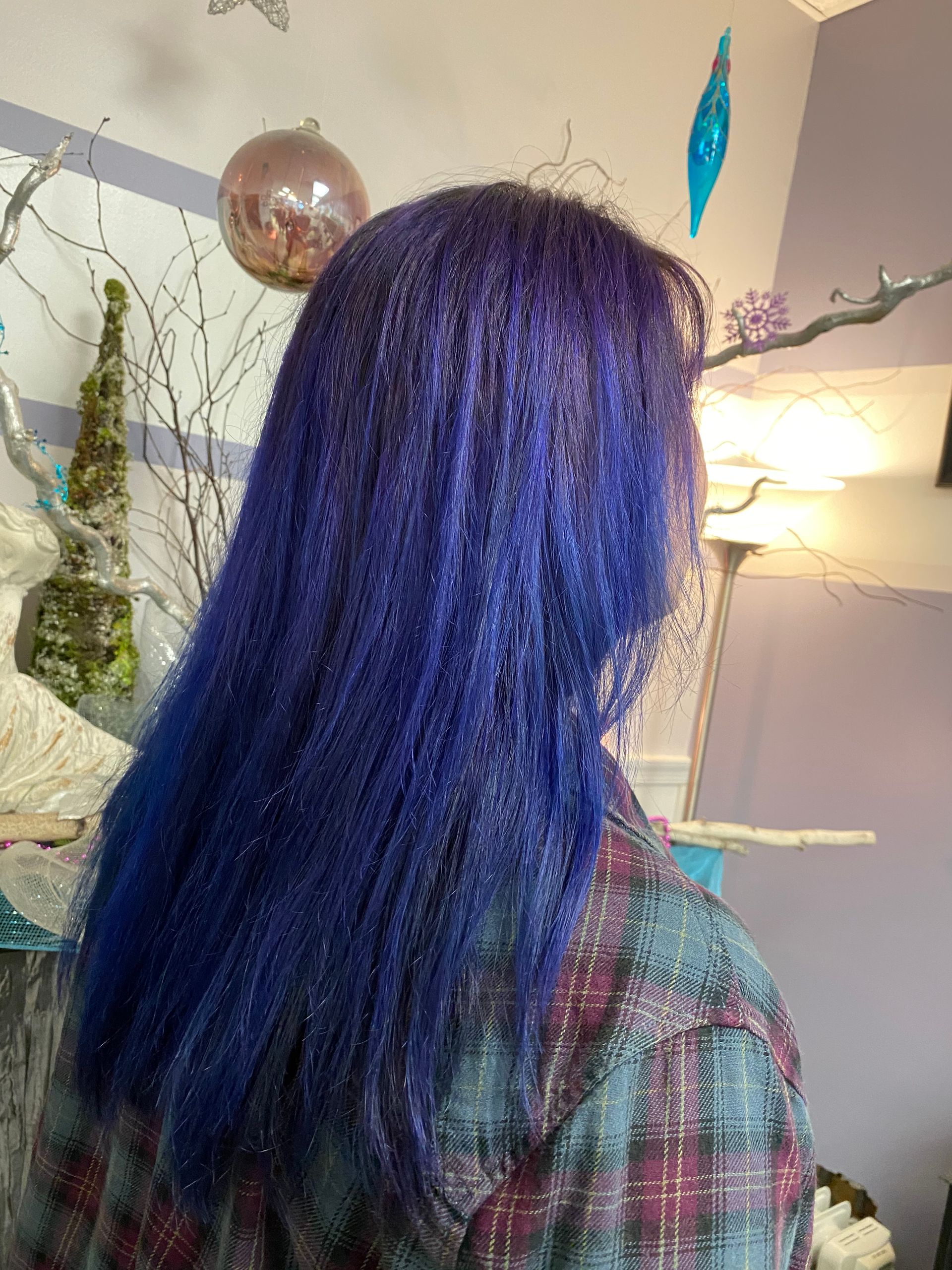 A woman with blue hair is wearing a plaid shirt.