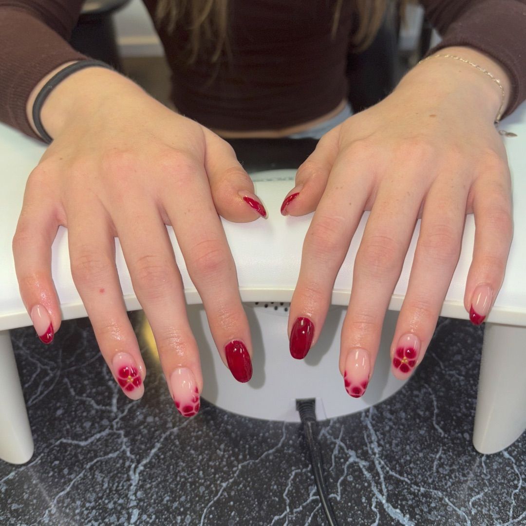 A woman's hands with red flowers manicure design.