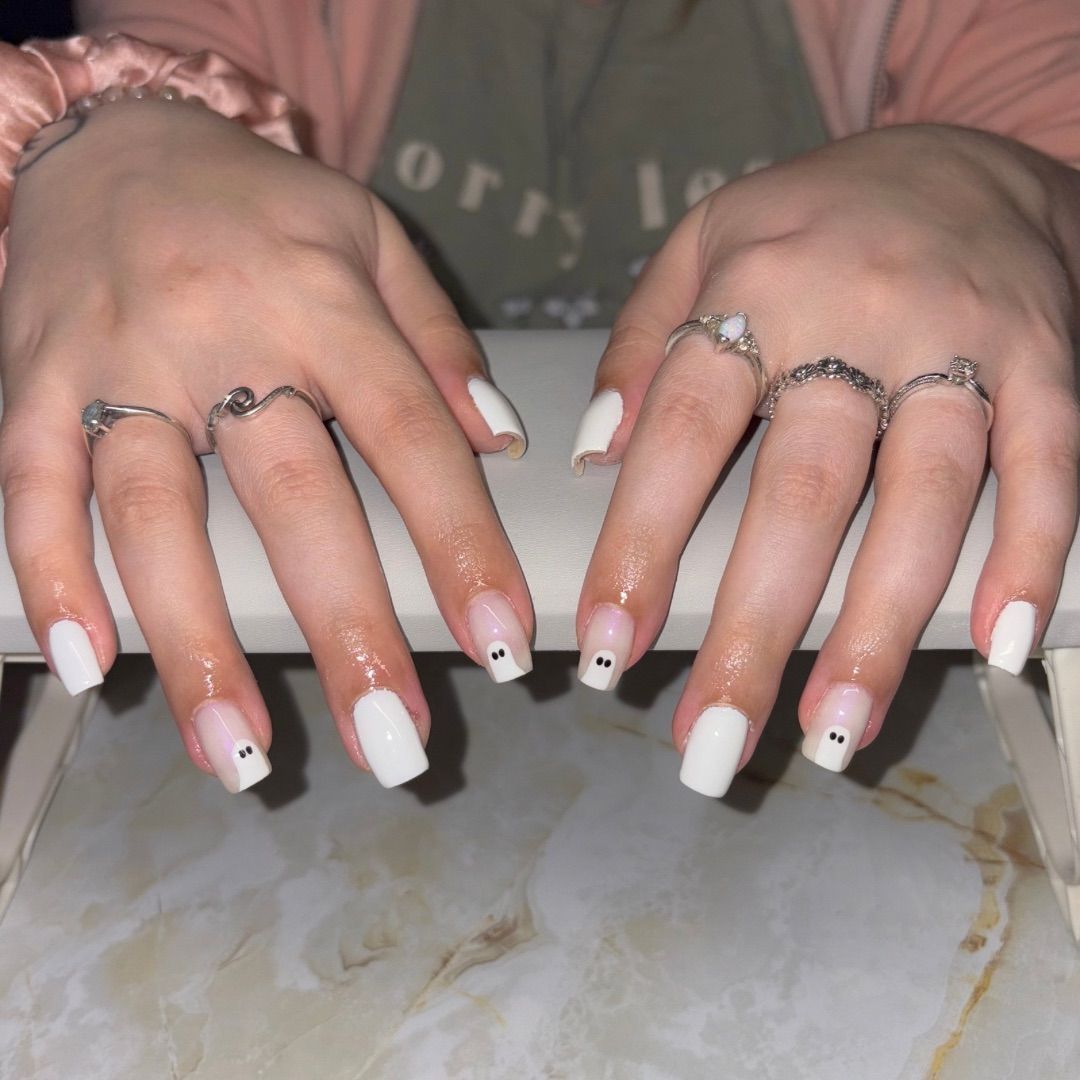 A woman's hands with a white ghost manicure design.