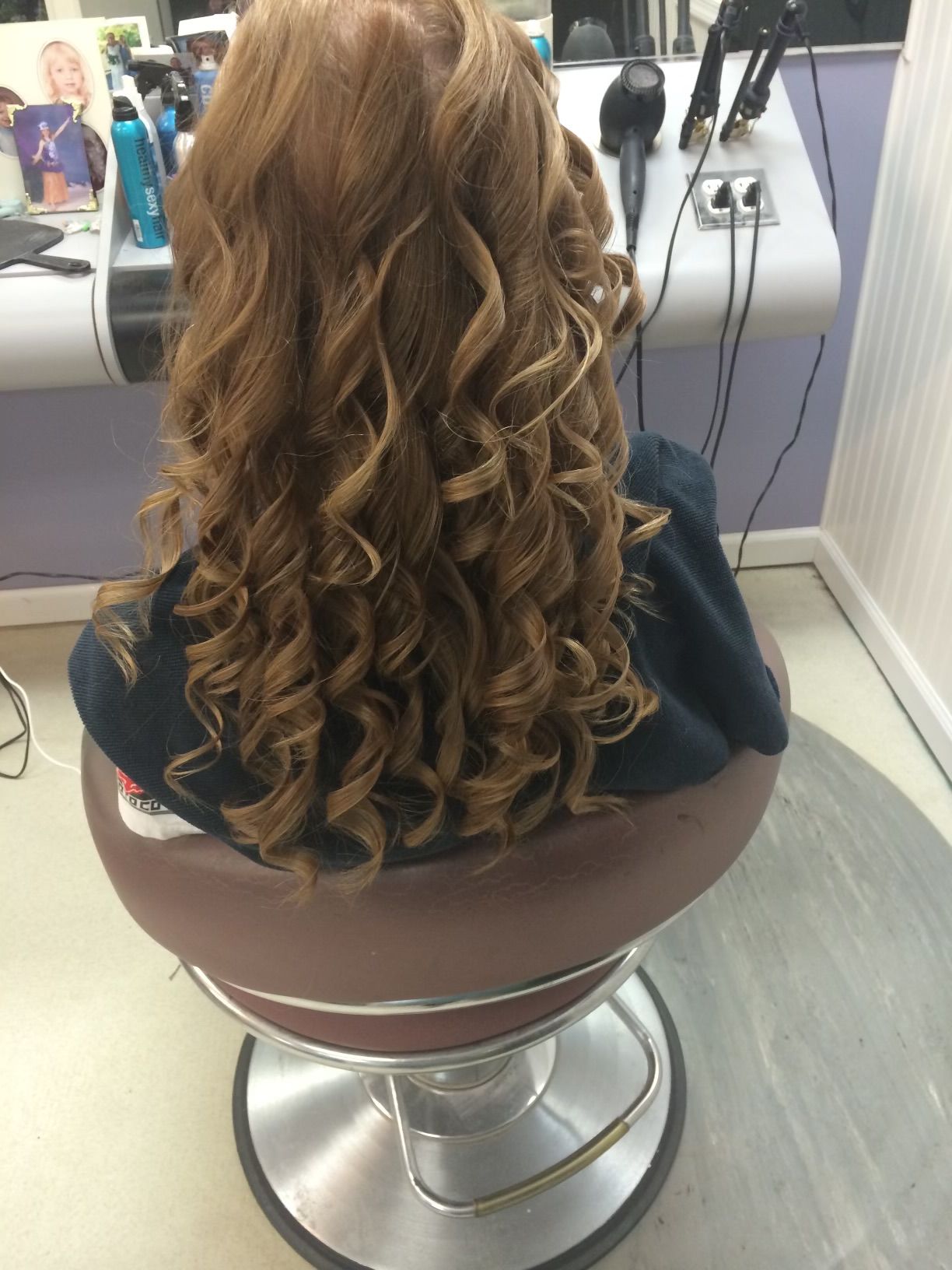 A woman with curly hair is sitting in a chair in a salon.