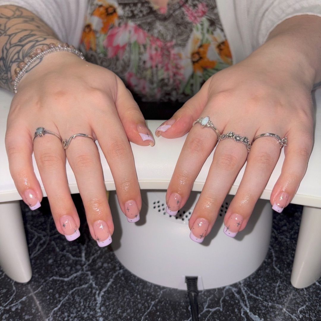 A woman's hands with silver stars manicure design.