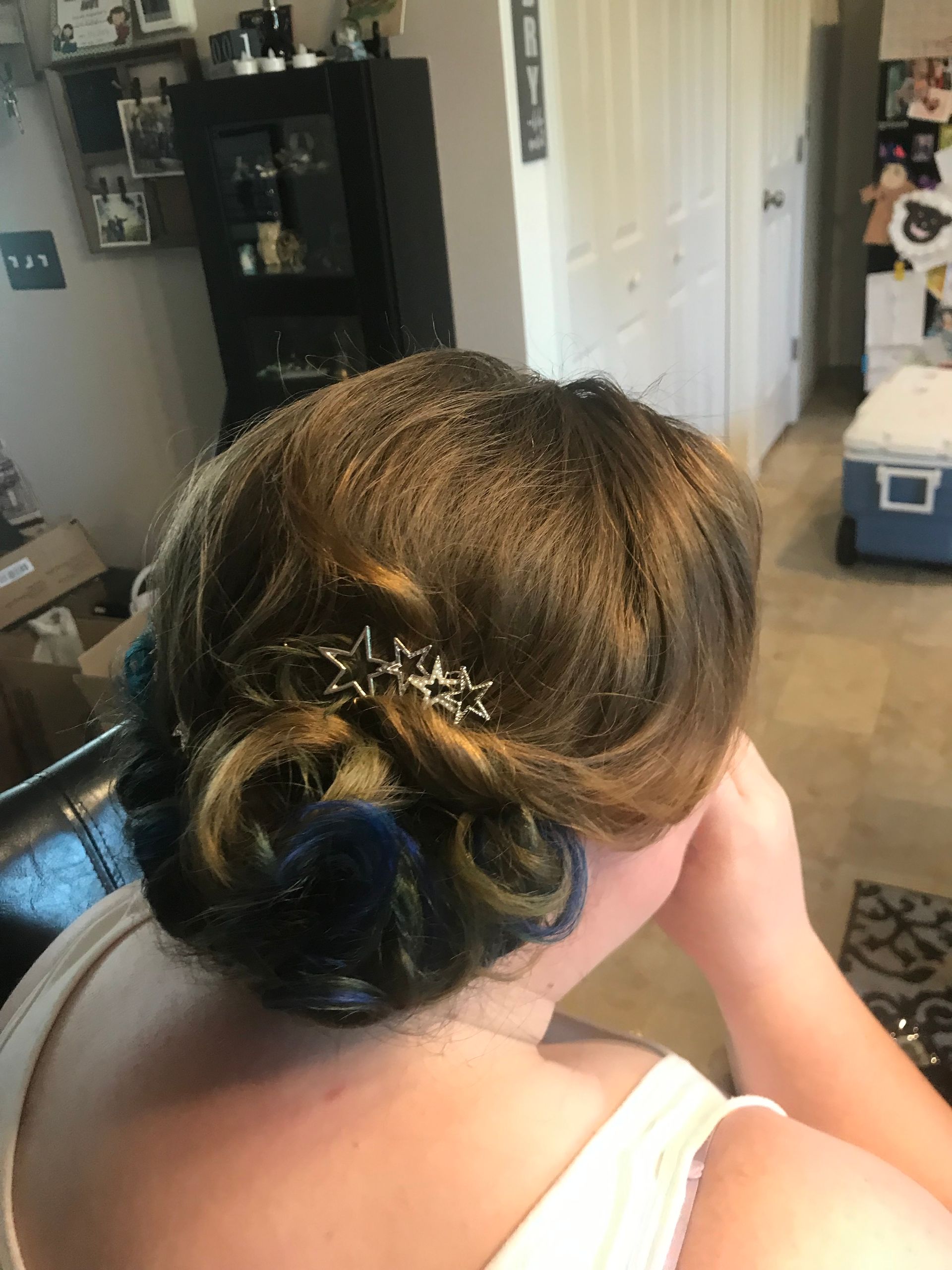A woman with blue hair is wearing a bun with a comb in her hair.