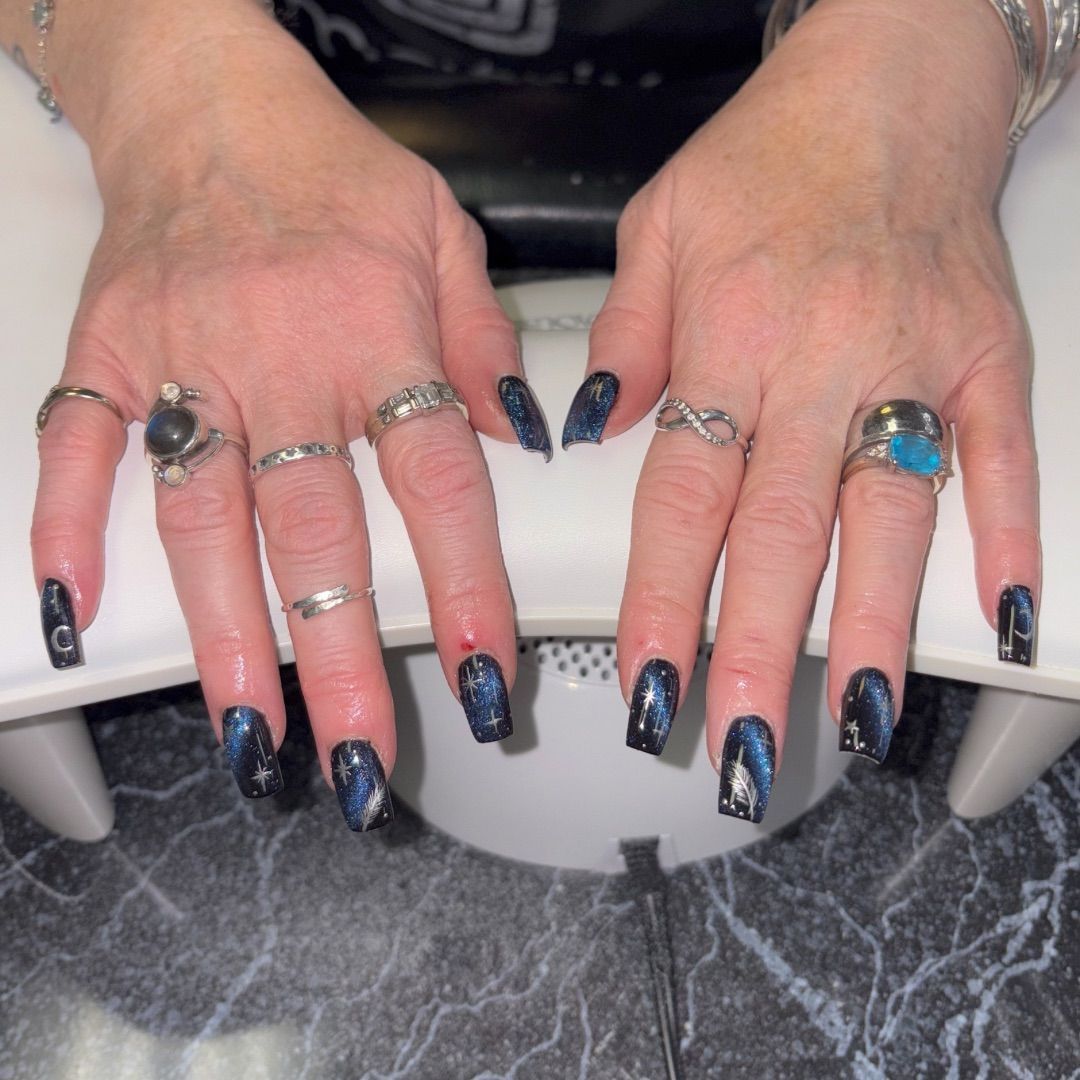 A woman's hands with a night sky manicure design.