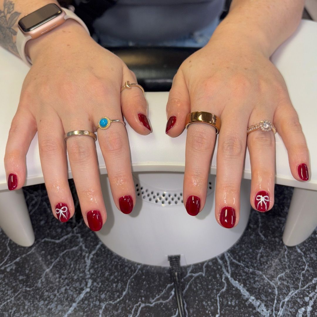 A woman's hands with red bows manicure design.