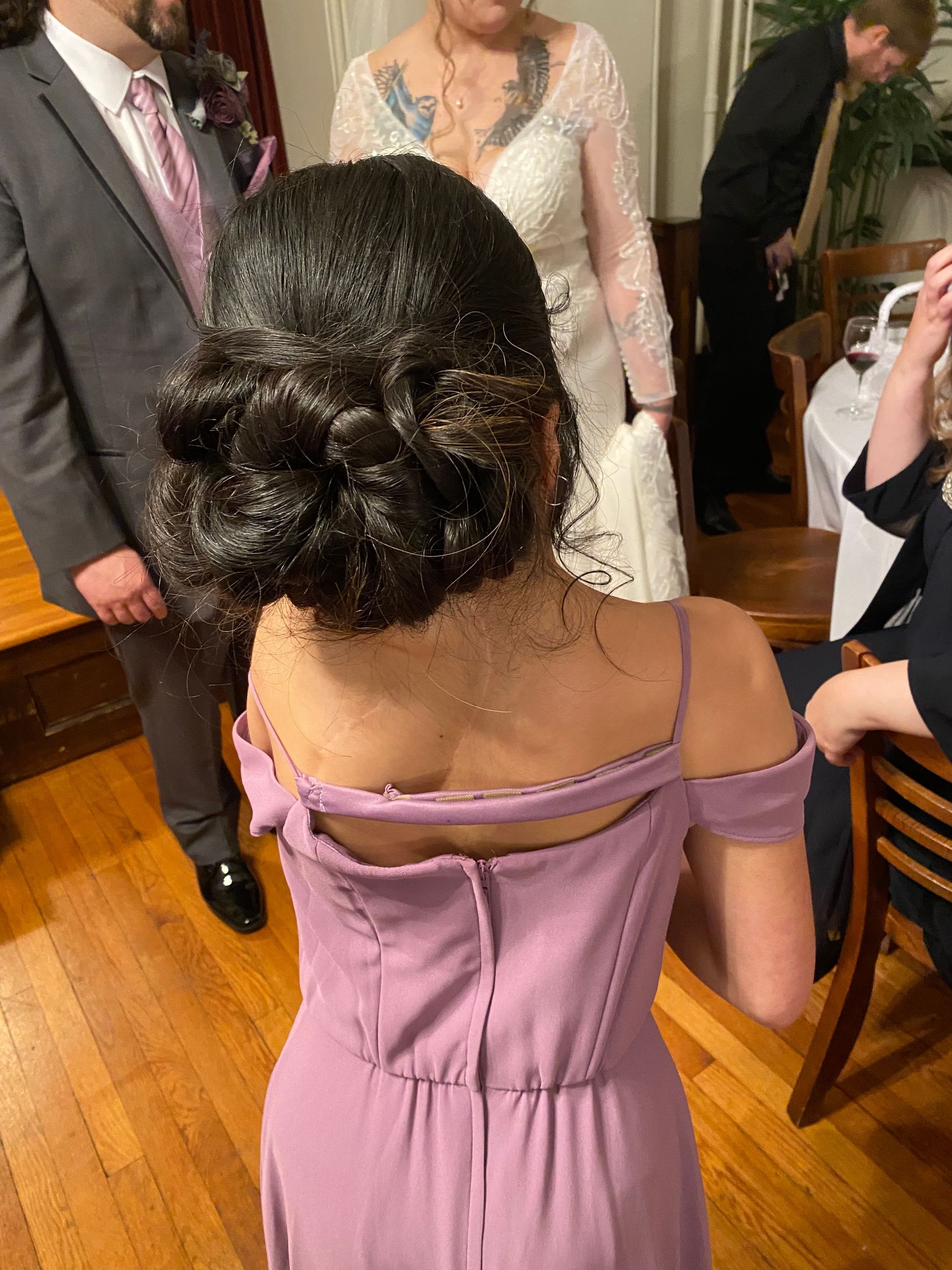 A woman in a purple dress is standing in a room with other people.