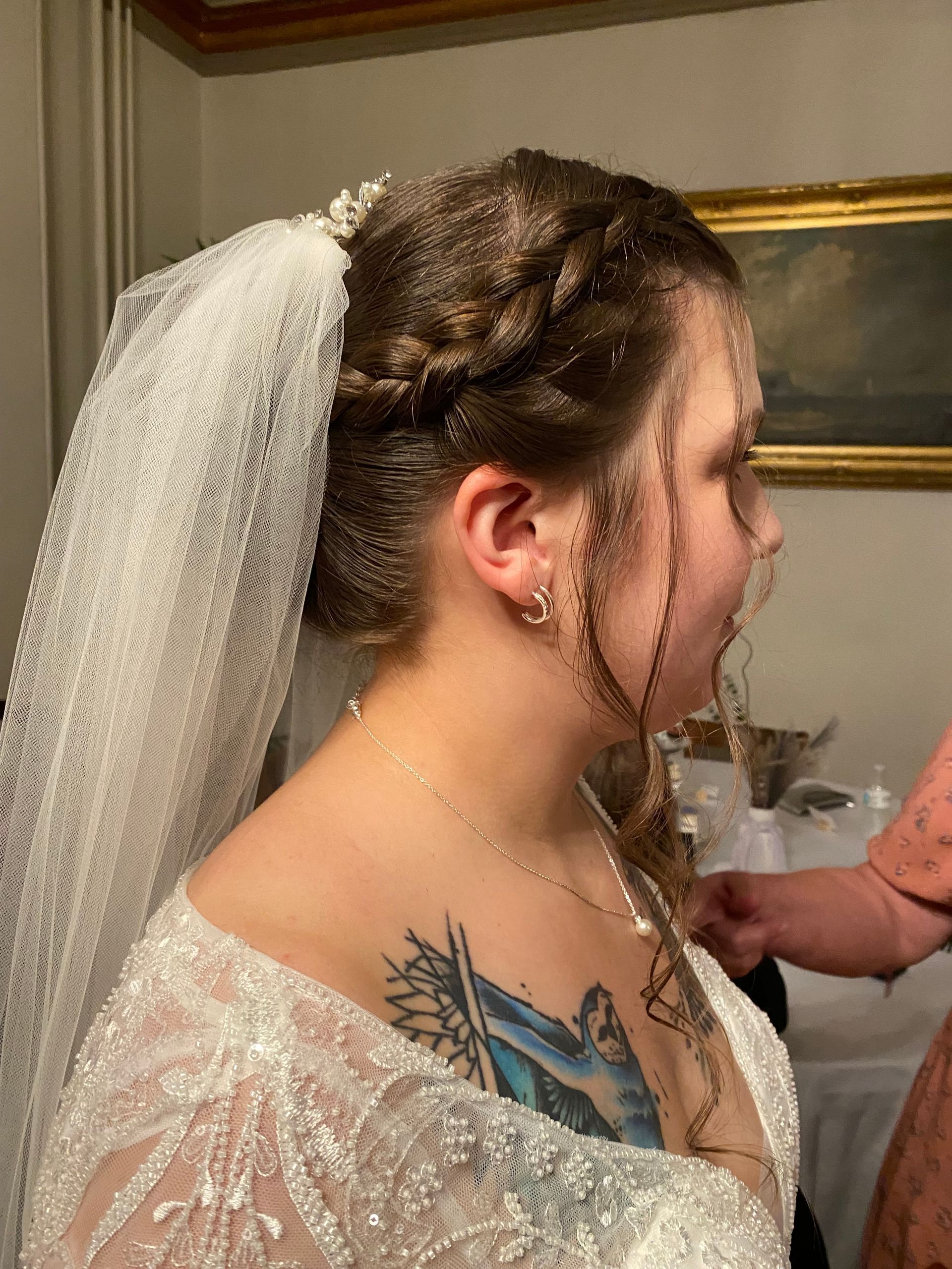 A woman in a wedding dress and veil is getting her hair done.