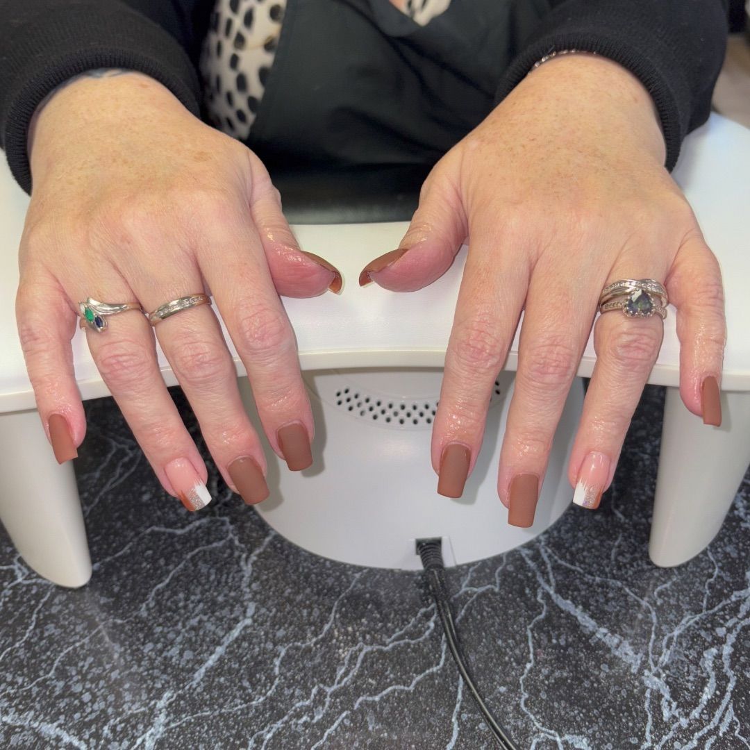 A woman's hands with a matte brown manicure design.