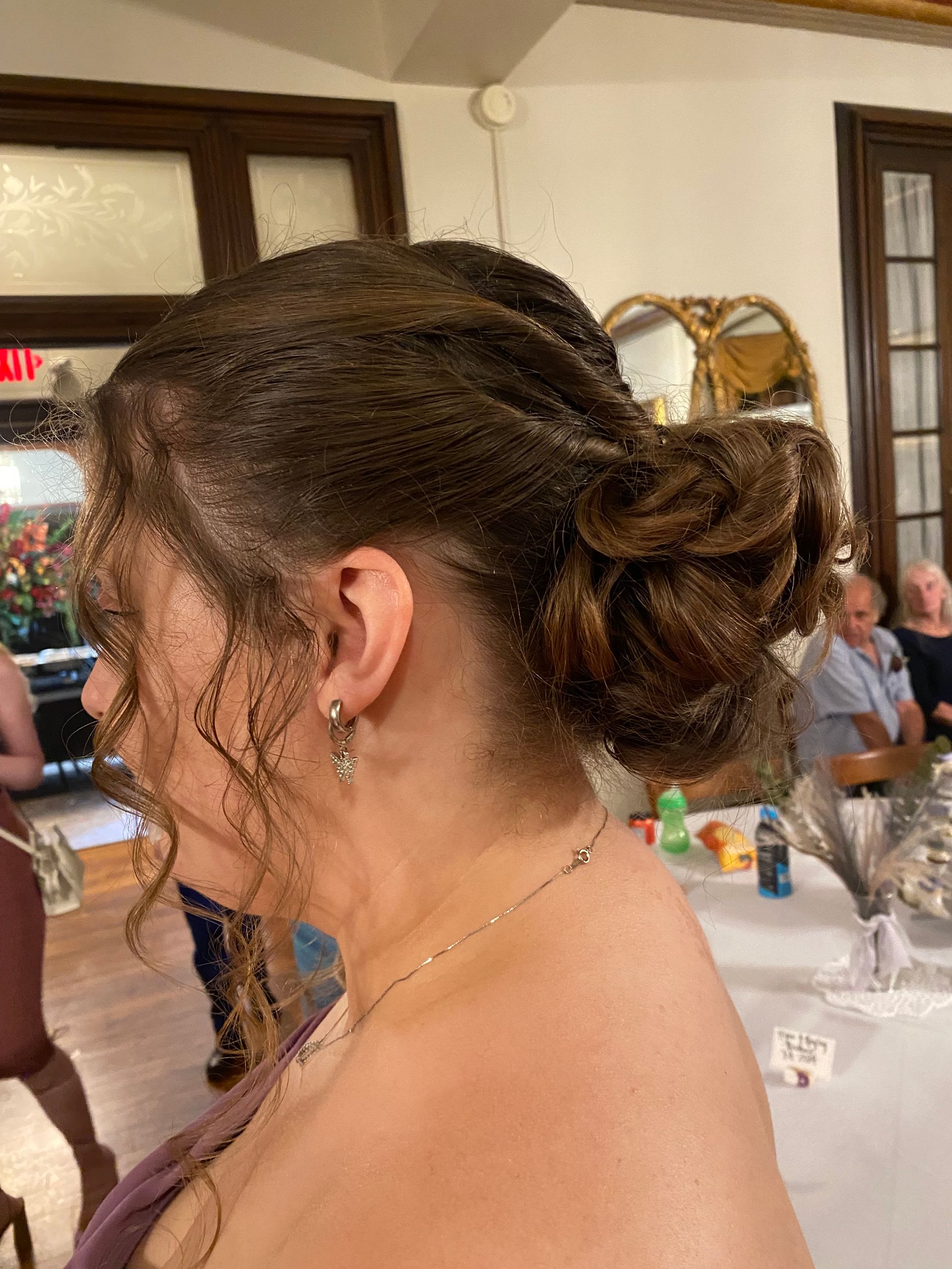 A woman with her hair in a bun is standing in a room.