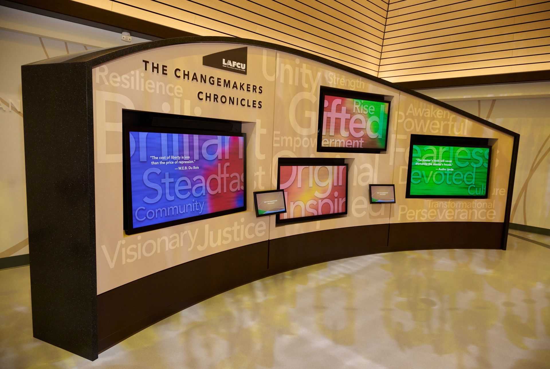 Curved museum display wall with colorful framed panels and text about changemaking and visionary leadership