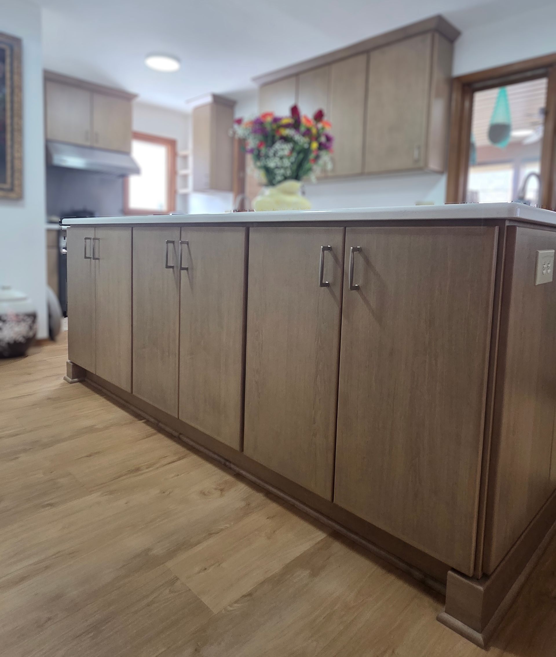 Kitchen island with wood cabinets and a vase of colorful flowers in a bright home interior
