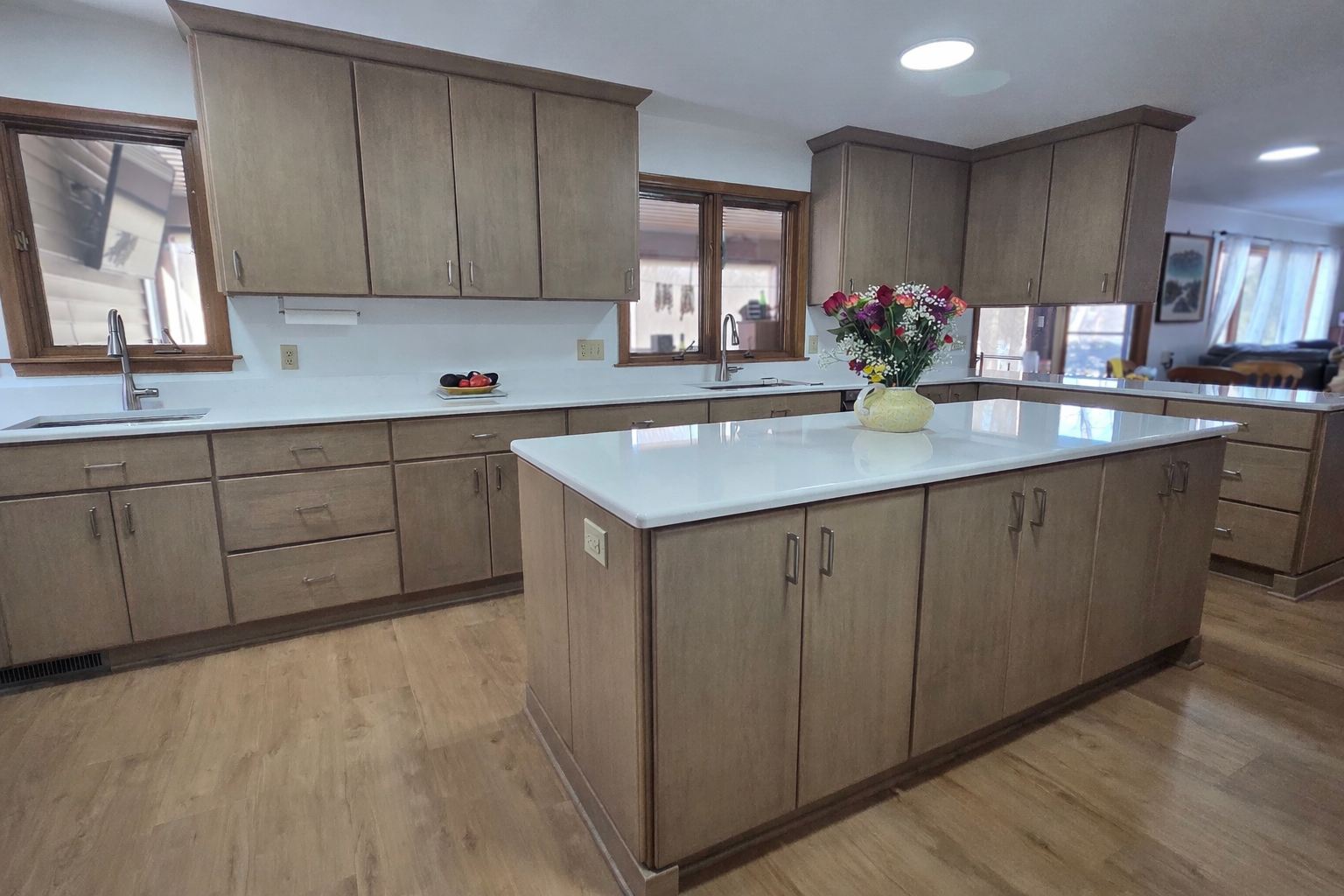 Bright kitchen with wood cabinets, large island, white countertops, and a vase of flowers