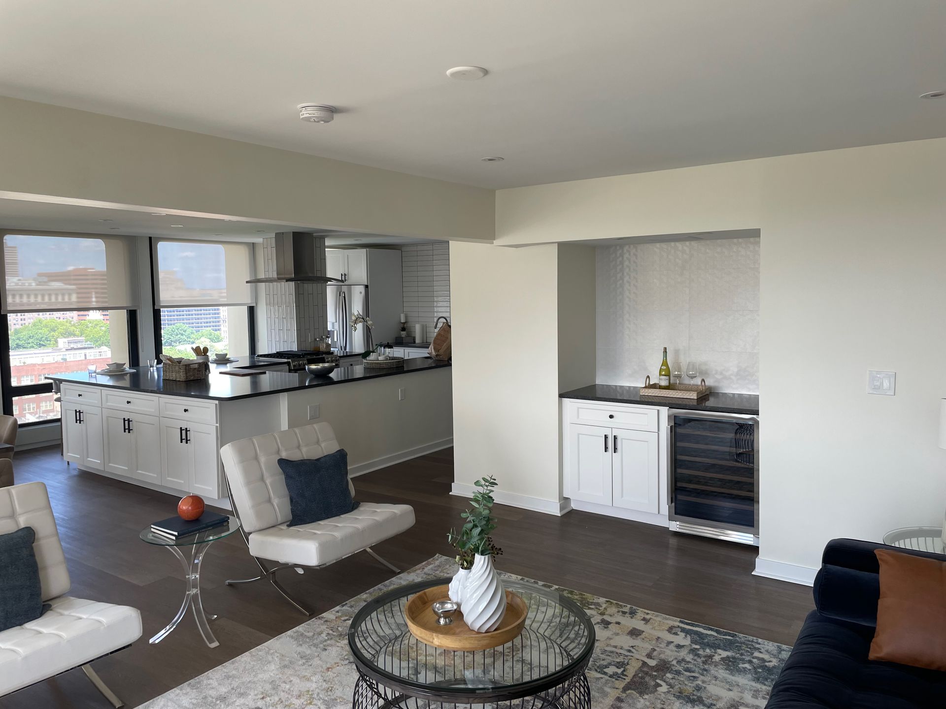 A living room with a couch , chairs , a coffee table and a kitchen.