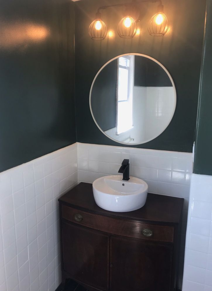 A bathroom with a sink and a round mirror
