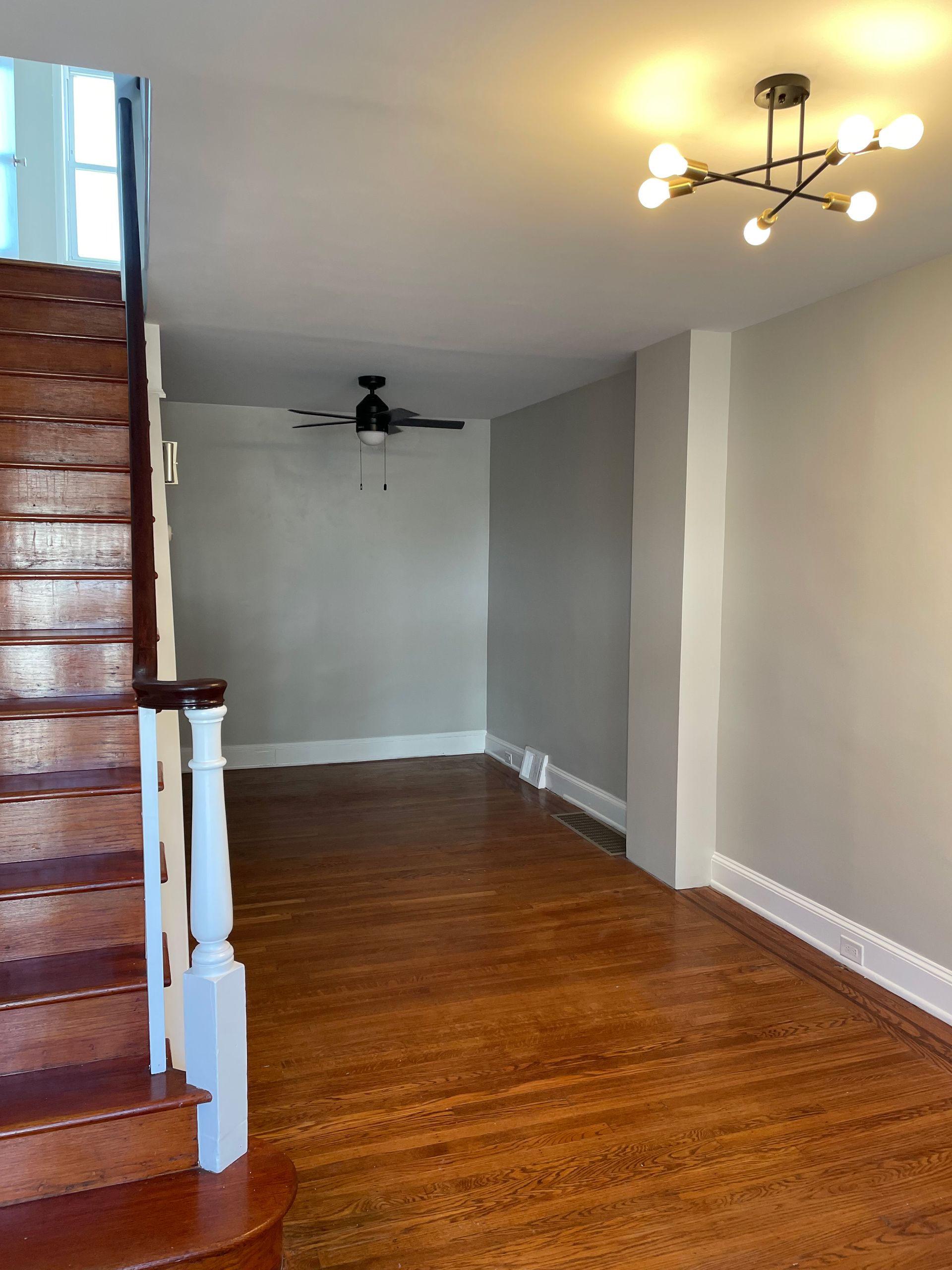 An empty room with stairs and a ceiling fan