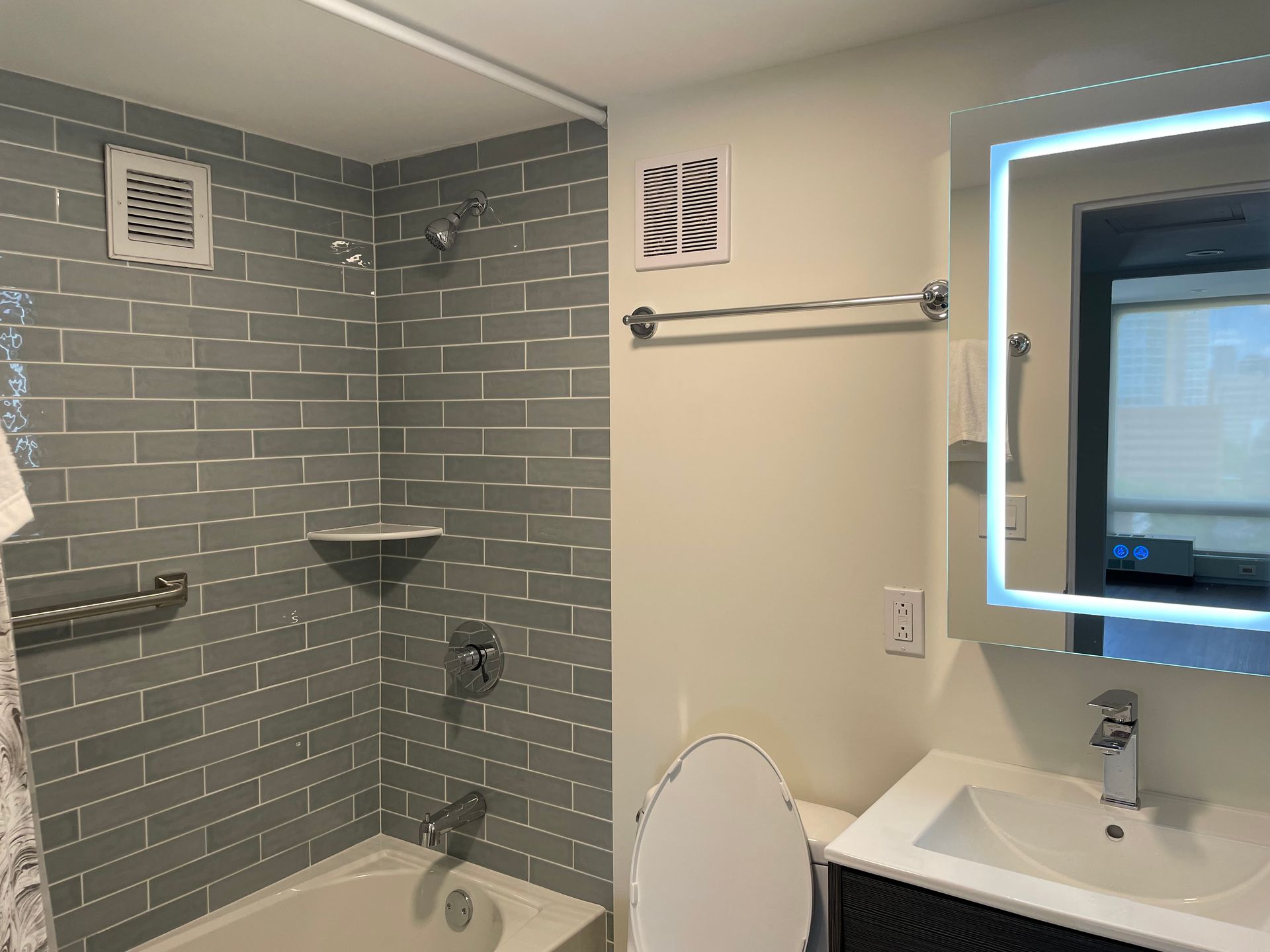 A bathroom with a sink , toilet , shower and mirror.