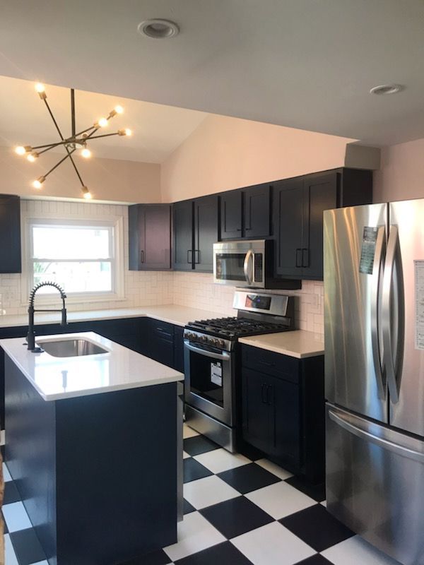 A kitchen with black cabinets and stainless steel appliances