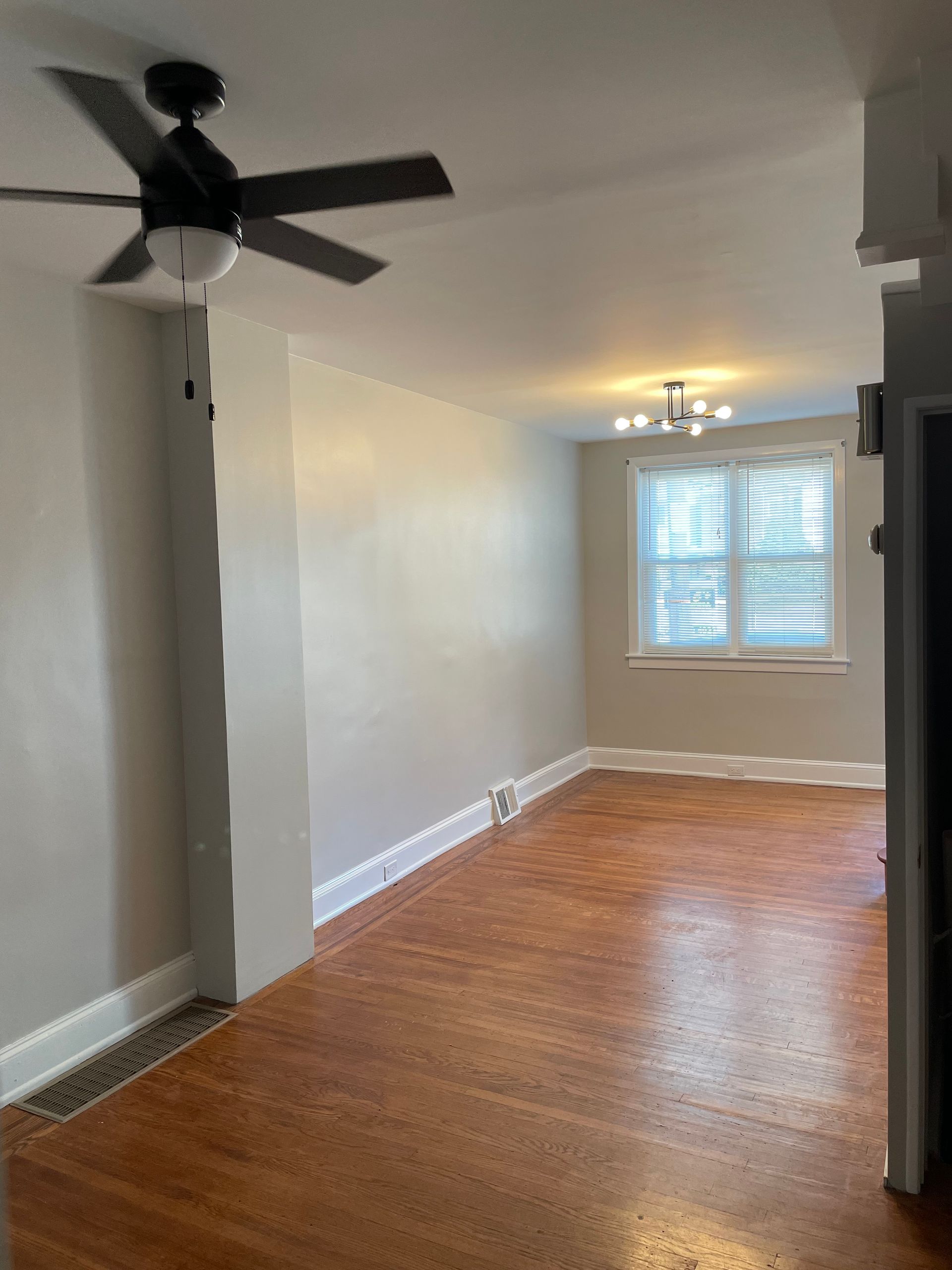 An empty room with a ceiling fan and a window.