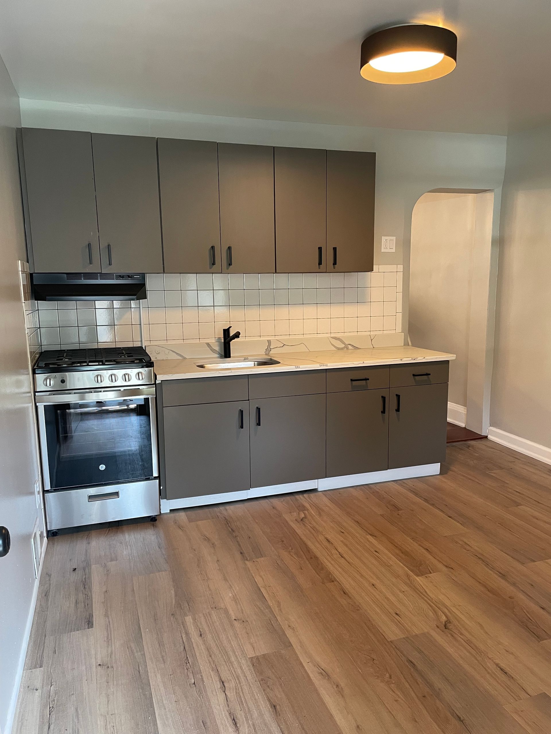 An empty kitchen with a stove , sink , and cabinets