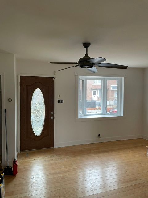 An empty living room with a ceiling fan and a window.