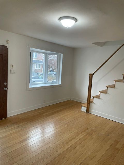 An empty living room with stairs and a window