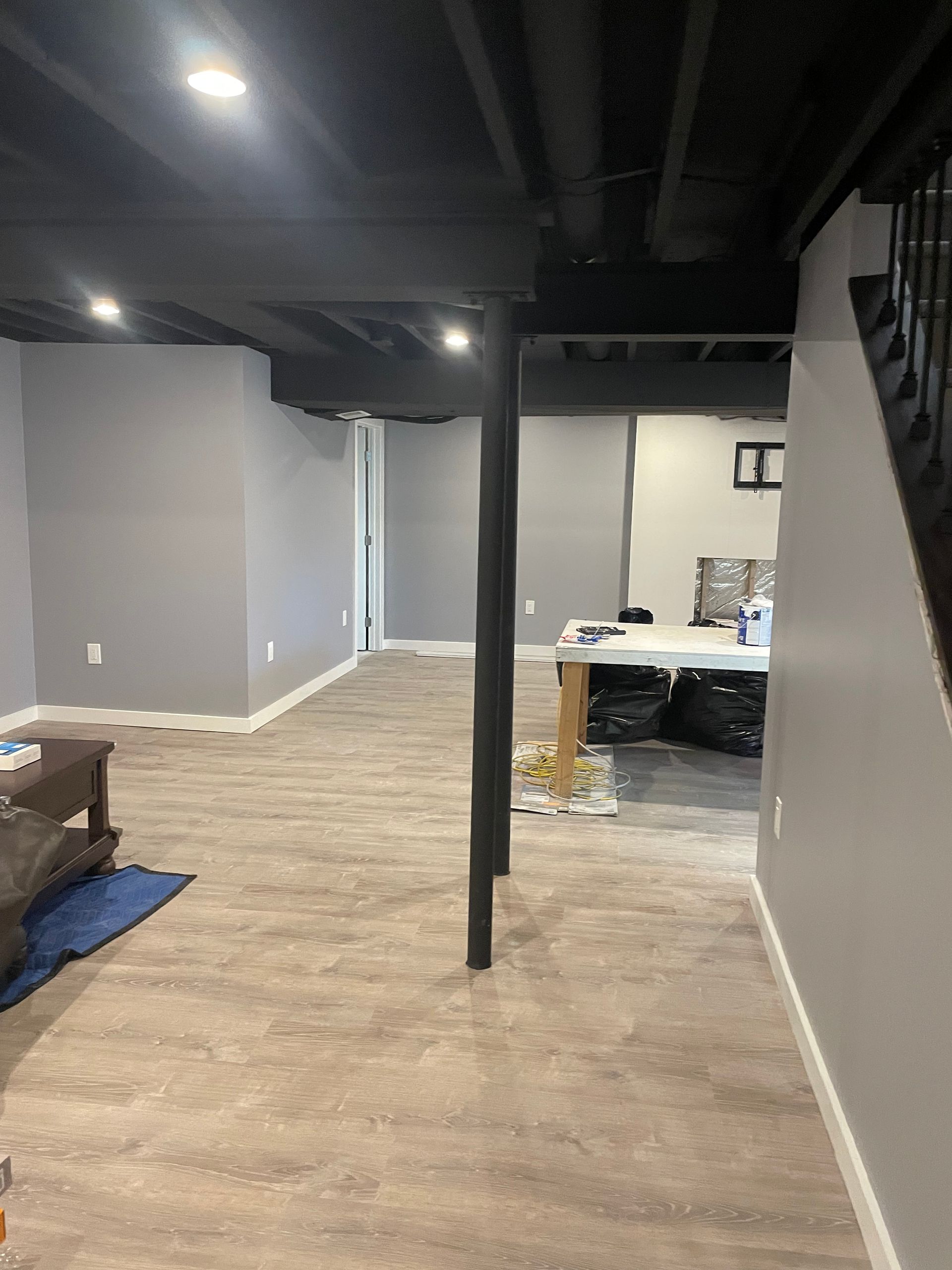 A basement with hardwood floors and a black ceiling.