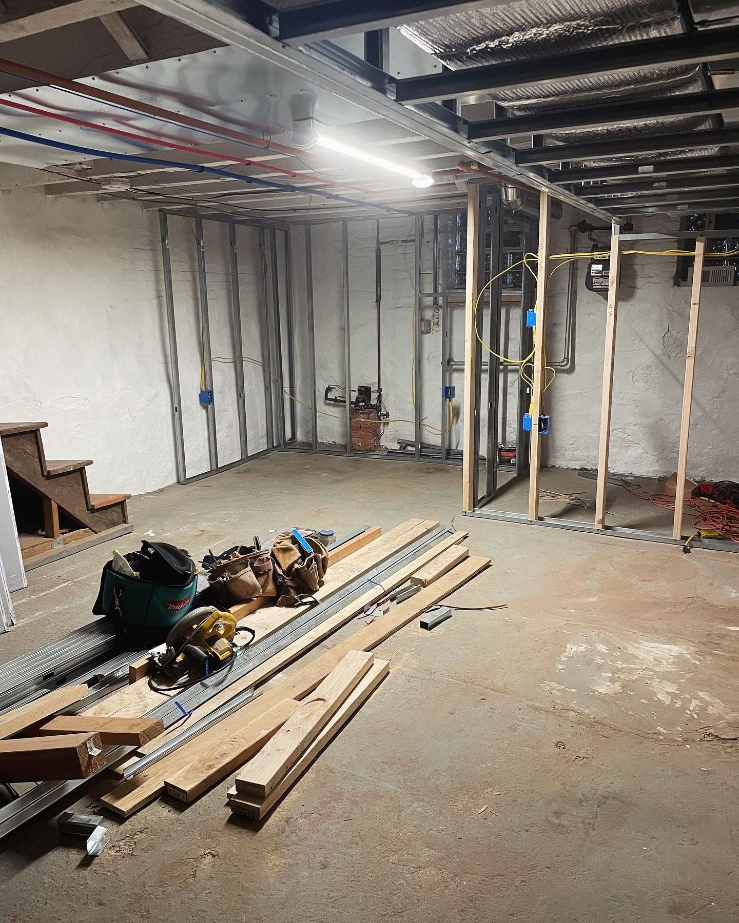 A basement under construction with wood and tools on the floor.