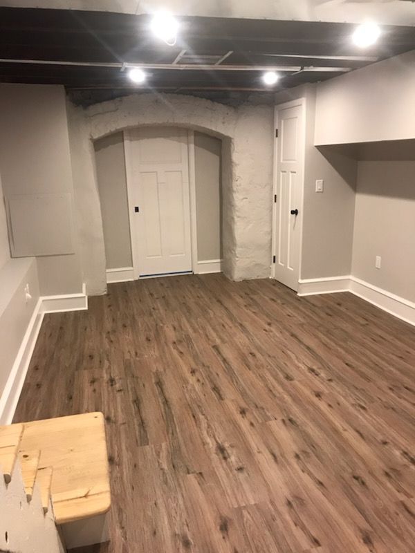 An empty basement with hardwood floors and white trim.